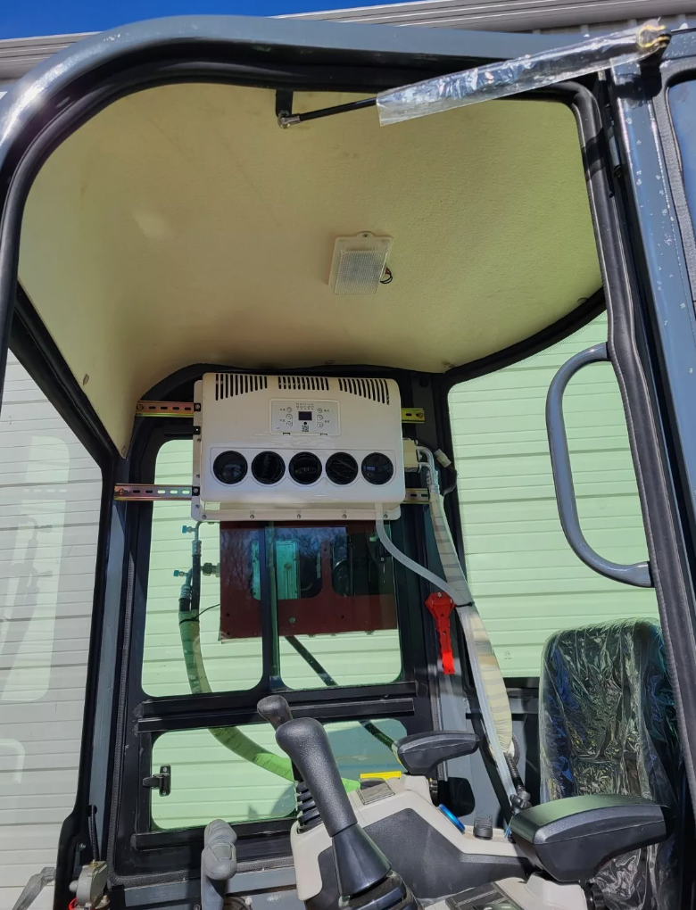 QK18RXS-C cab interior: overhead air-conditioning unit with five vents, dome light, joystick and seat