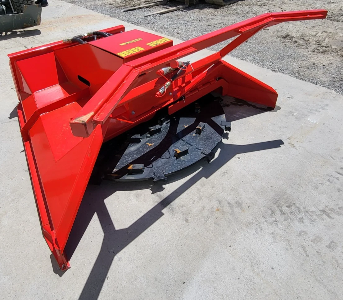 Red disc mulcher at an angle: steel push frame, hydraulic hoses and the toothed black cutting disc beneath