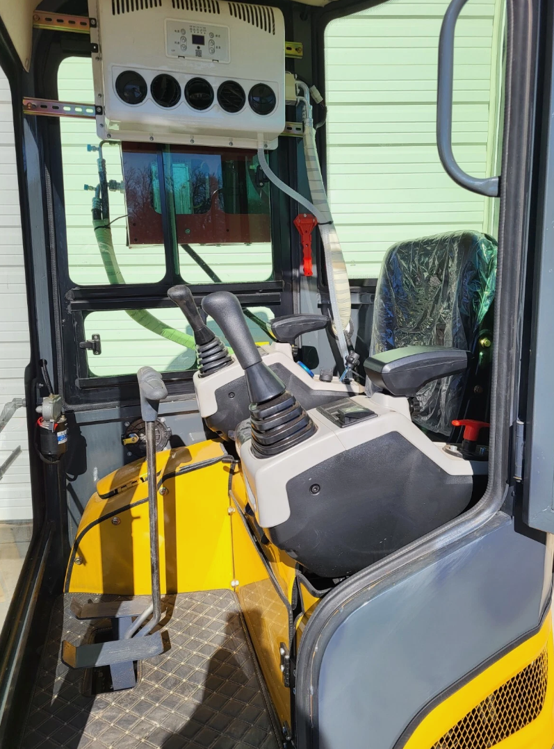 QK18RXS-C cab: pilot joysticks, wrapped suspension seat, travel levers and the overhead air conditioner