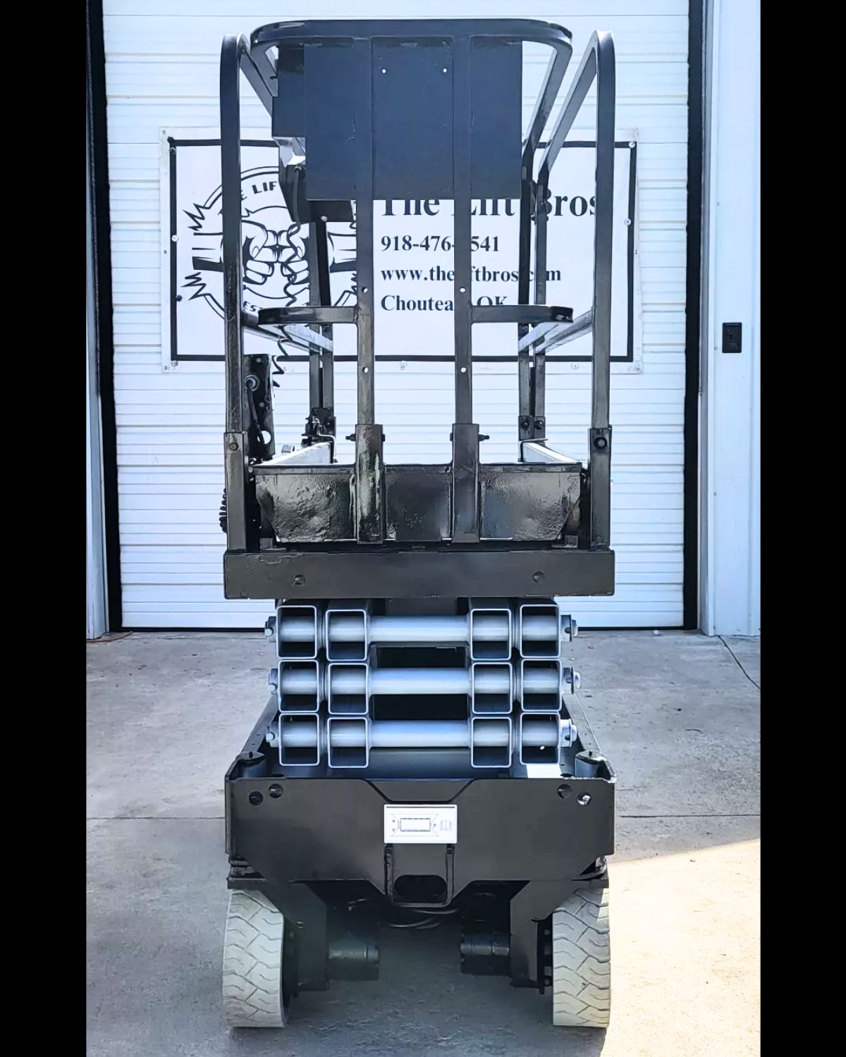 Genie GS-1930 scissor lift from behind, black platform lowered over the silver scissor stack, guardrails up