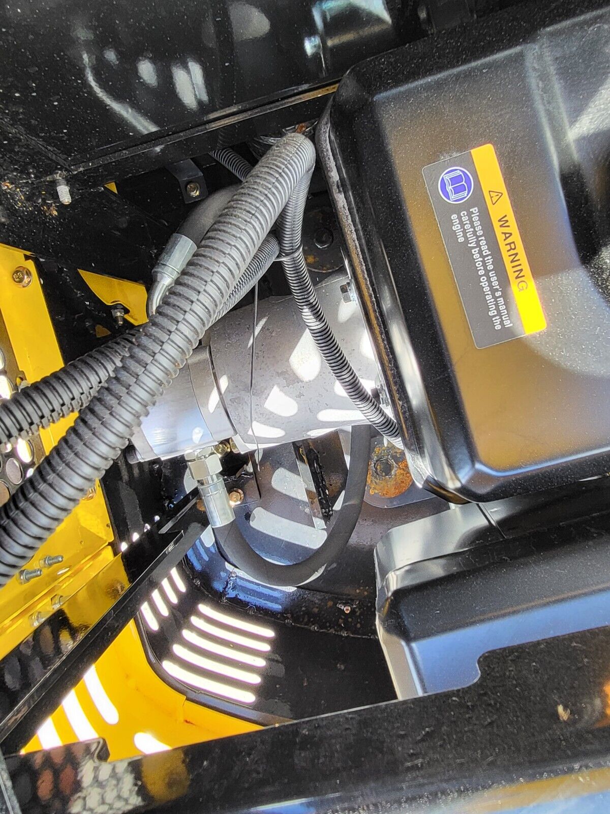 AGT QH12R engine bay with hydraulic hoses, muffler and warning label on the engine cover