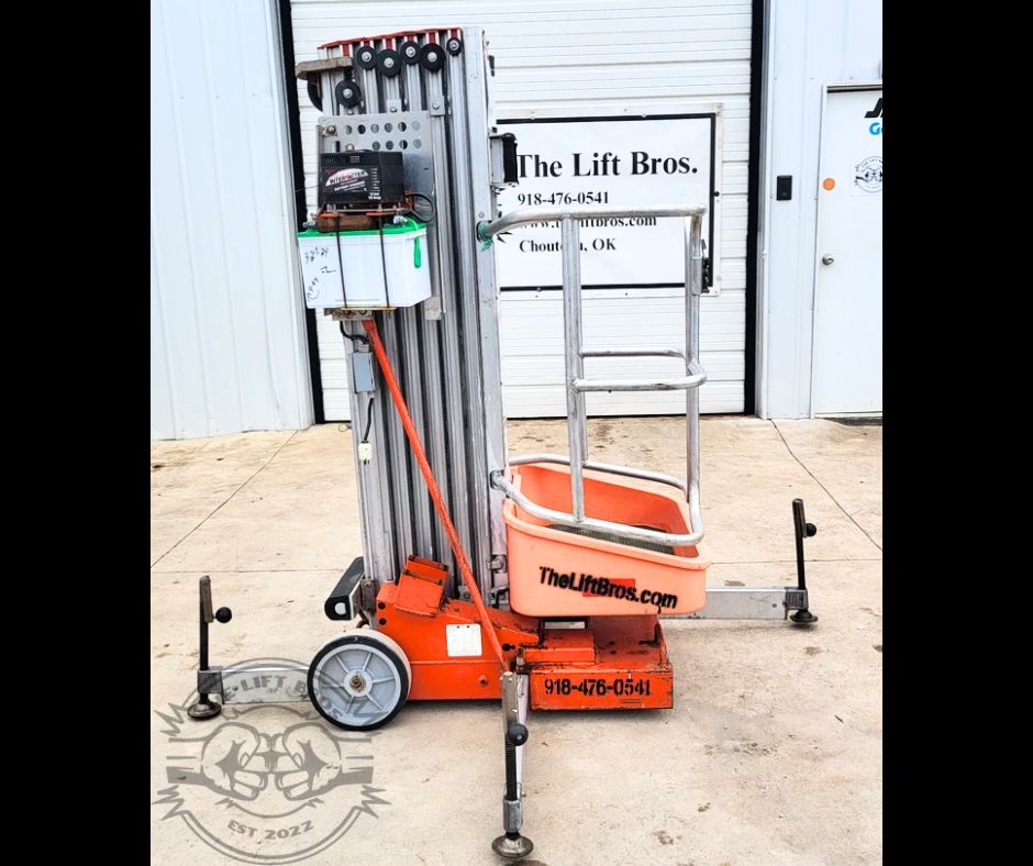Used push-around vertical mast lift with orange platform basket, aluminum mast and outriggers on the shop lot