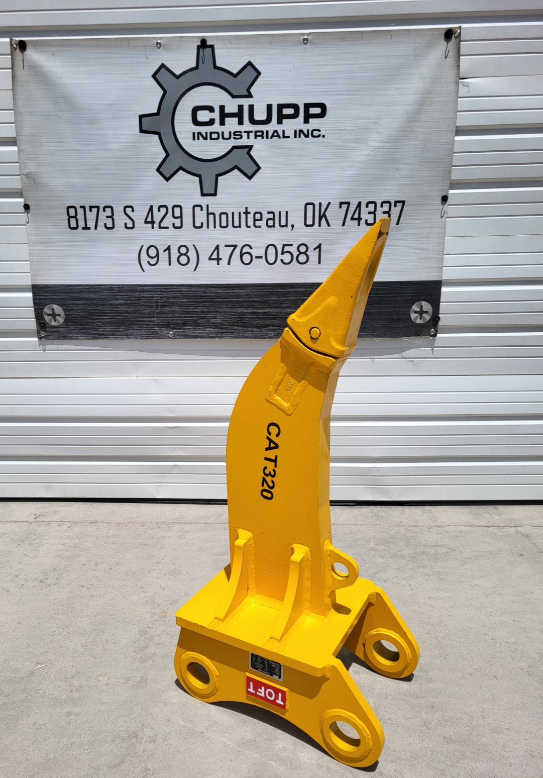 Red excavator ripper attachment with rotating tines and safety warning label visible