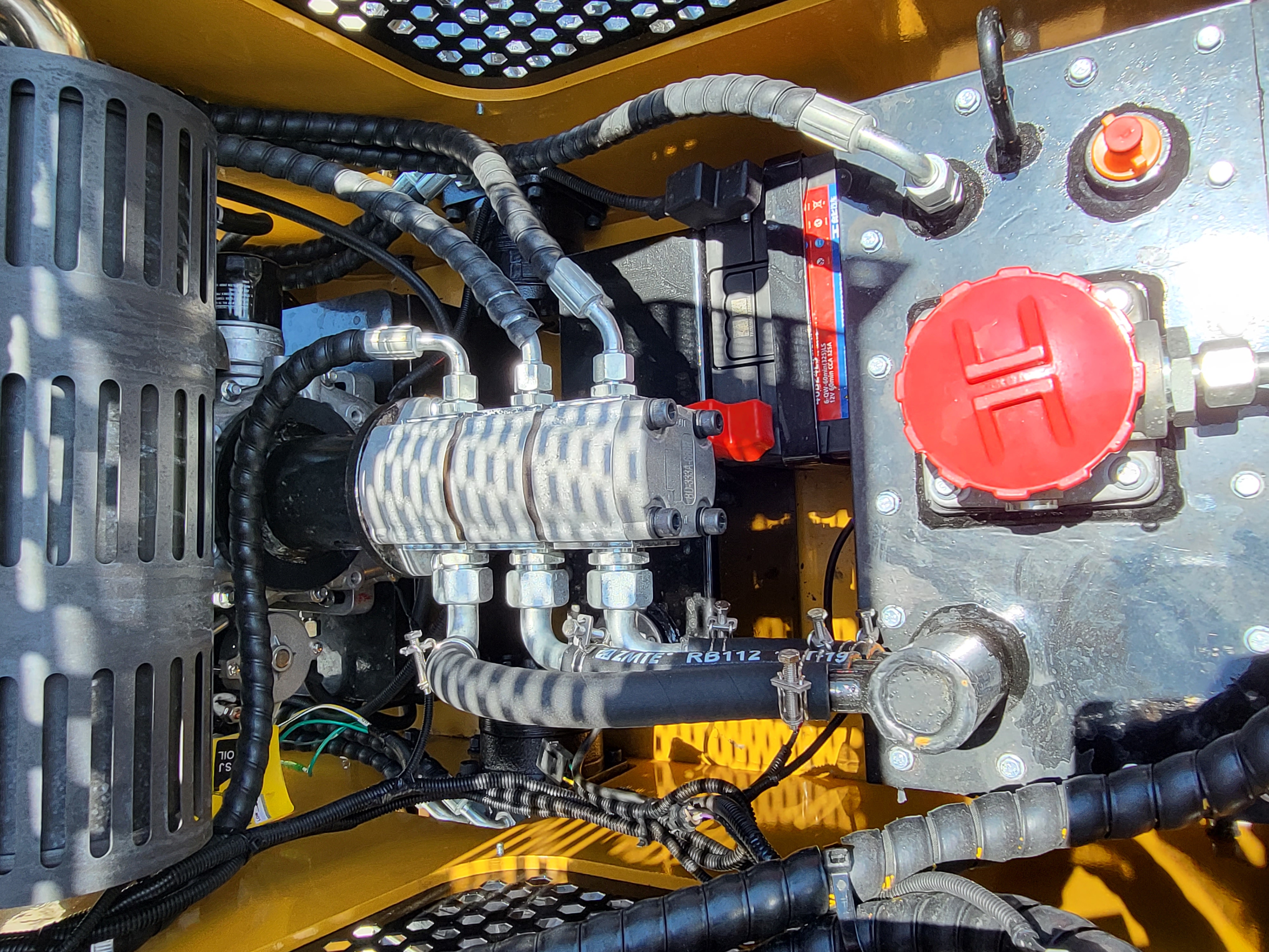 AGT CRT23: triple-section hydraulic gear pump, 12V battery and red hydraulic fill cap beside the muffler shield