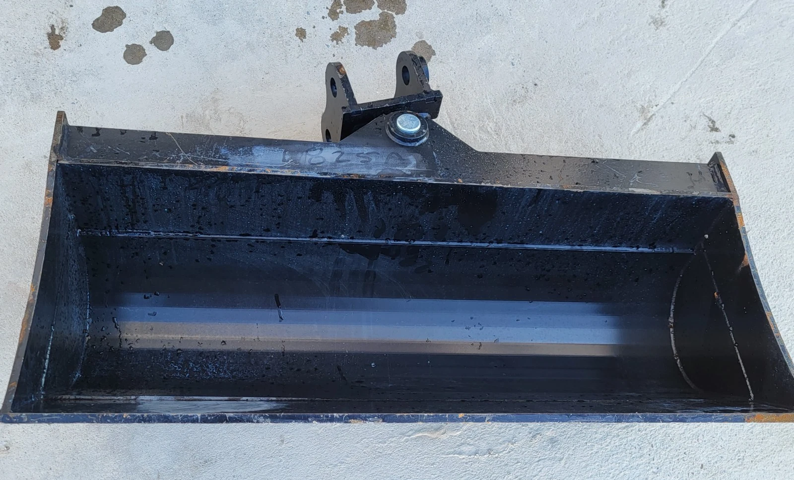 Tilt bucket from above: smooth open interior, no teeth, single pin-on mounting bracket at the back