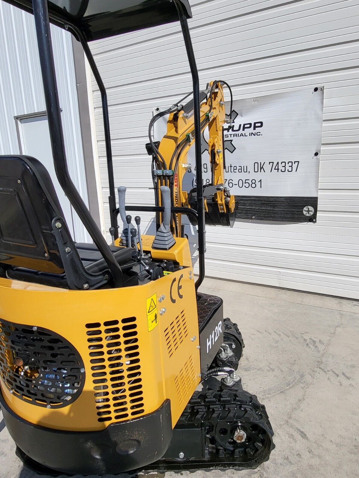 AGT H12R mini excavator vented engine cover, seat and joysticks, with the boom extended over the rubber tracks