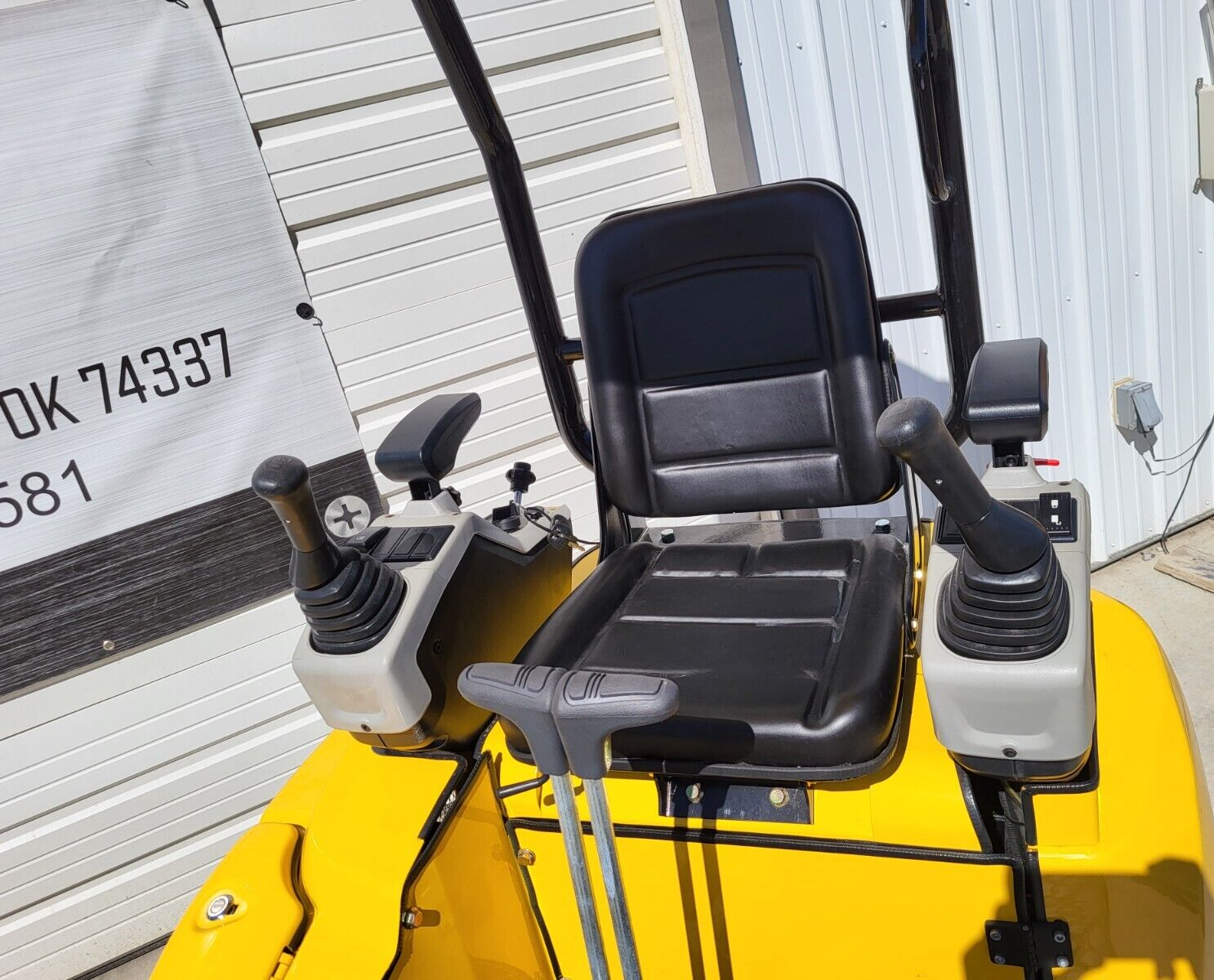 FF15 operator station: black vinyl seat between twin joystick pods, two travel levers in front, throttle and hour meter