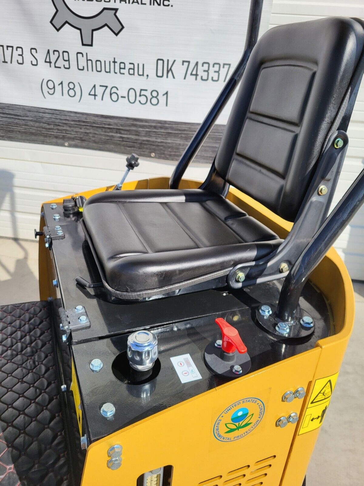 AGT H12R mini excavator seat on its hinged base, with red battery disconnect switch and hydraulic sight gauge