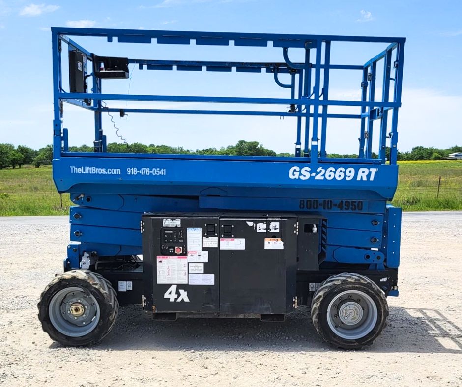 GS-2669 RT rough terrain scissor lift, blue, platform lowered with folding guardrails on four-wheel-drive lug tires
