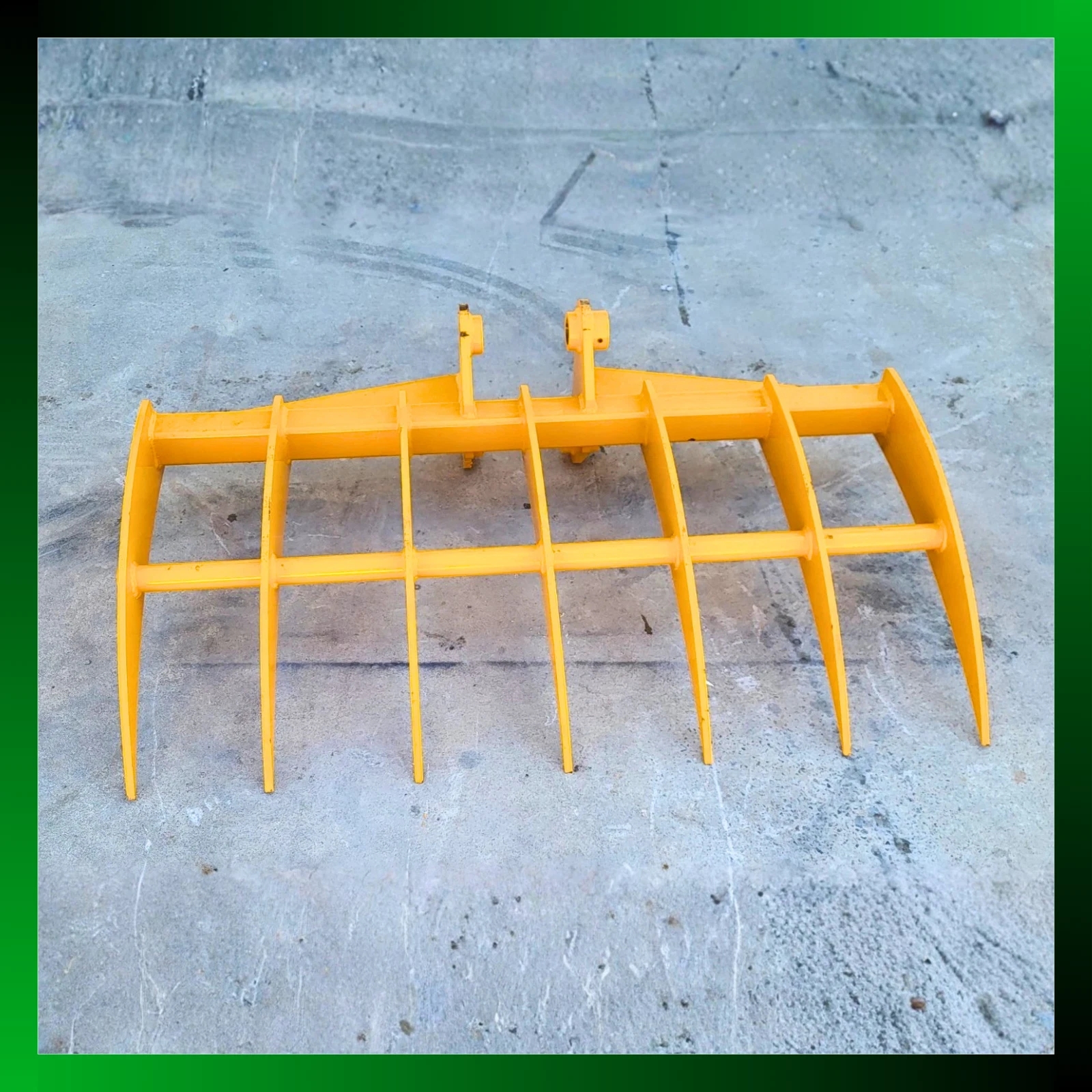 Yellow excavator root rake, seven curved tines on a tubular frame with twin pin bosses on the spine
