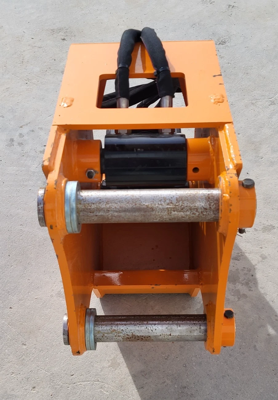 Wolverine attachment head from above: two mounting pins, hydraulic cylinder and sleeved hoses