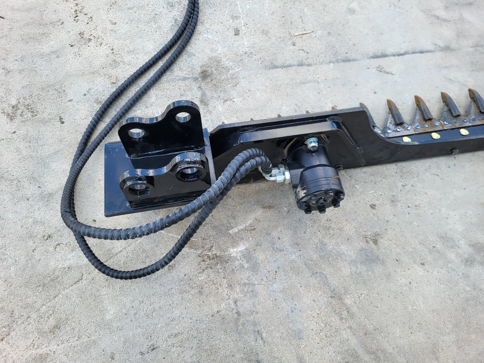 Sickle mower's pin-on mounting bracket and hydraulic drive motor, hoses looped out, cutter bar to the right
