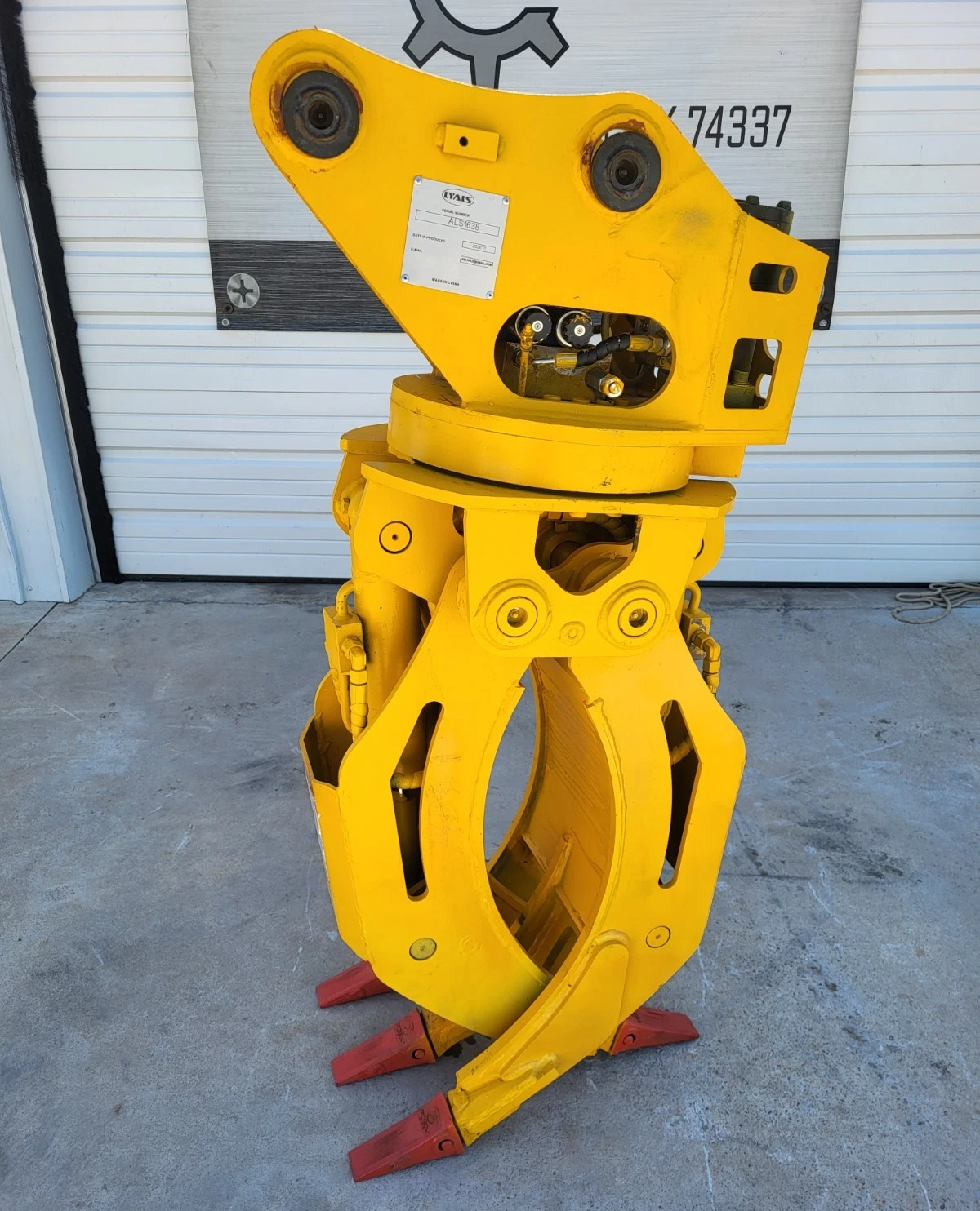 Yellow ALS1638 rotating grapple, jaws open, pin-on mount head and rotator bearing above red tooth tips