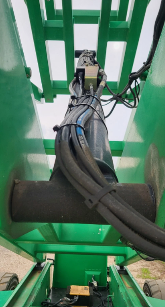 Underside of the scissor lift: hydraulic lift cylinder and hoses running up between the green scissor arms
