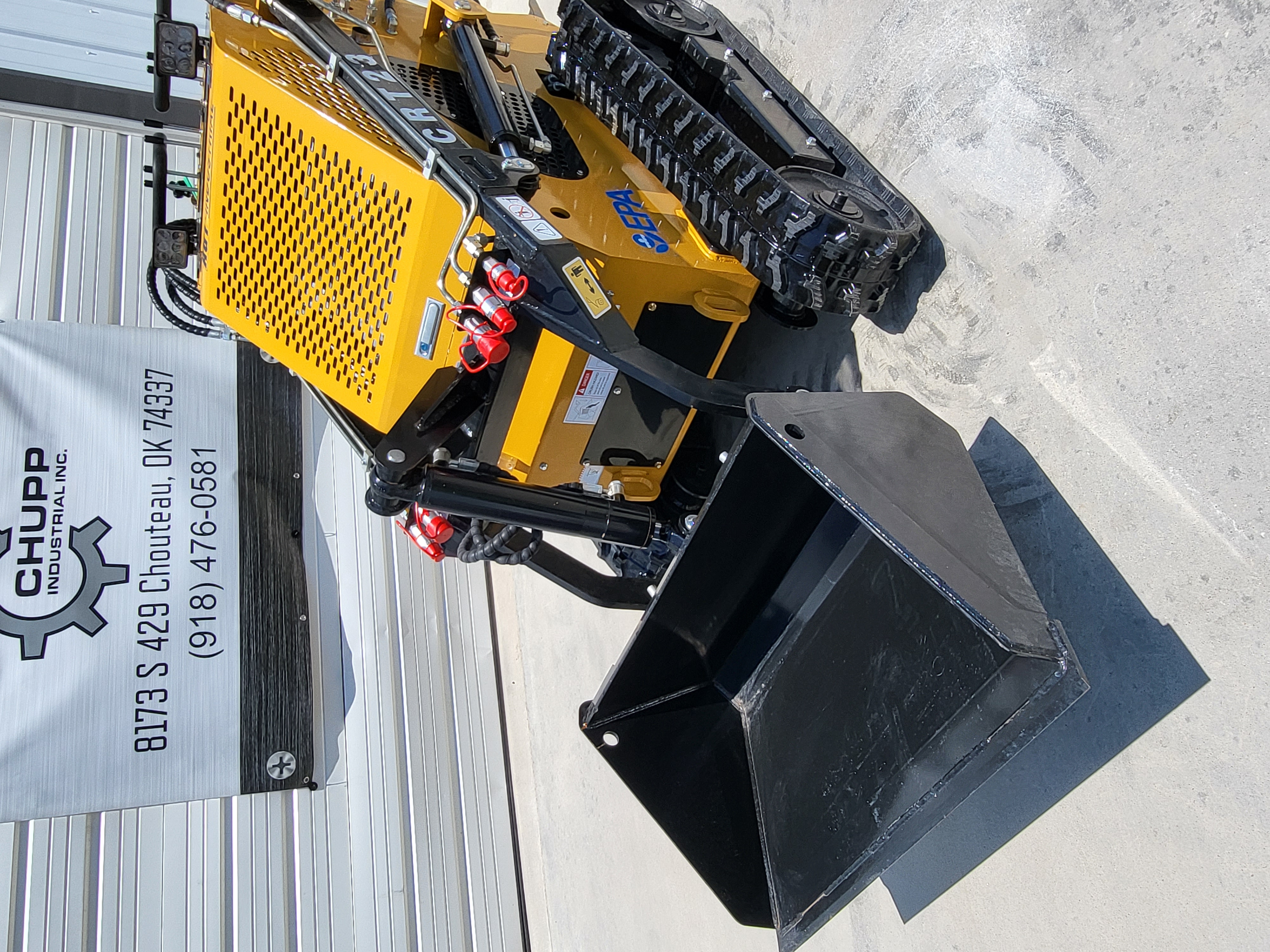 AGT CRT23 mini skid steer with black dirt bucket lowered, perforated engine hood, LED work lights and rubber tracks