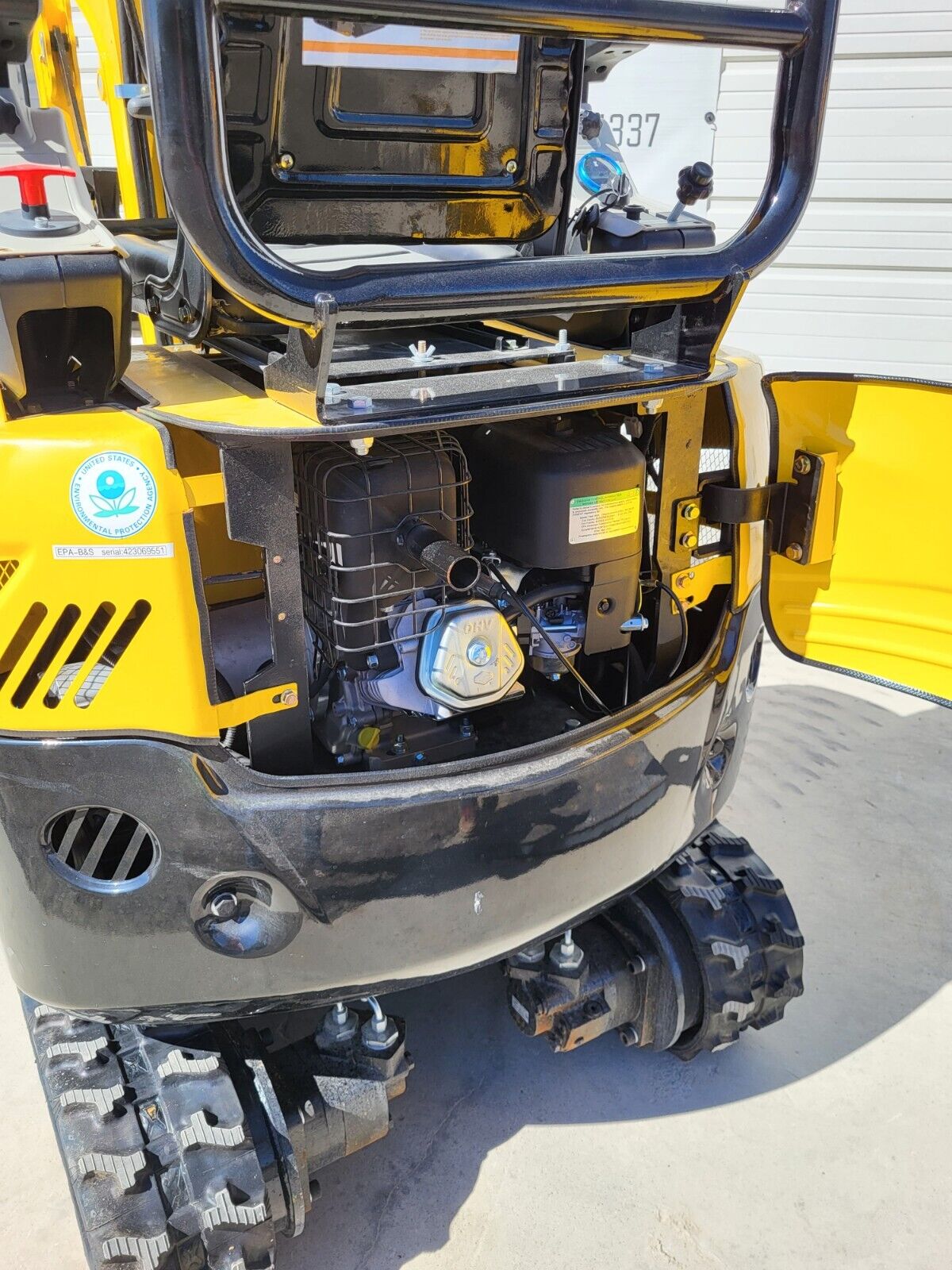 FF15 rear engine bay open: Briggs & Stratton OHV engine with air cleaner and muffler, EPA label, final drive and tracks
