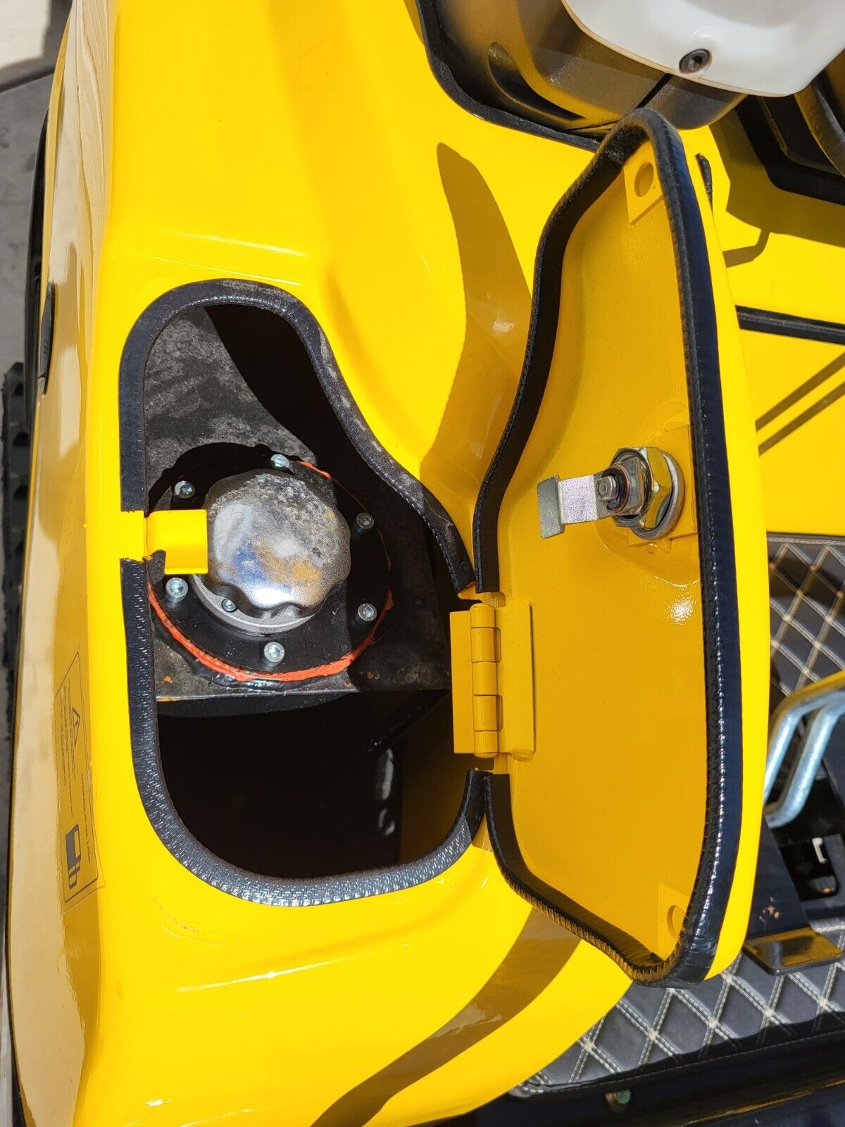 FF15 side access door open: hinged yellow panel over the chrome fill cap and its red sealing gasket