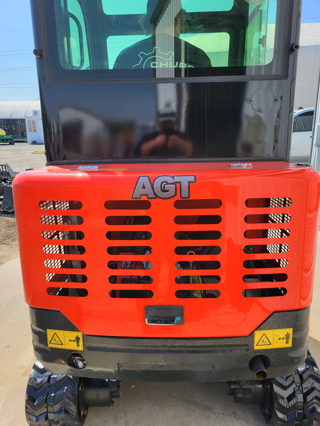 Mini excavator rear: red engine cover with AGT badge, vented panel, safety decals, rubber tracks below