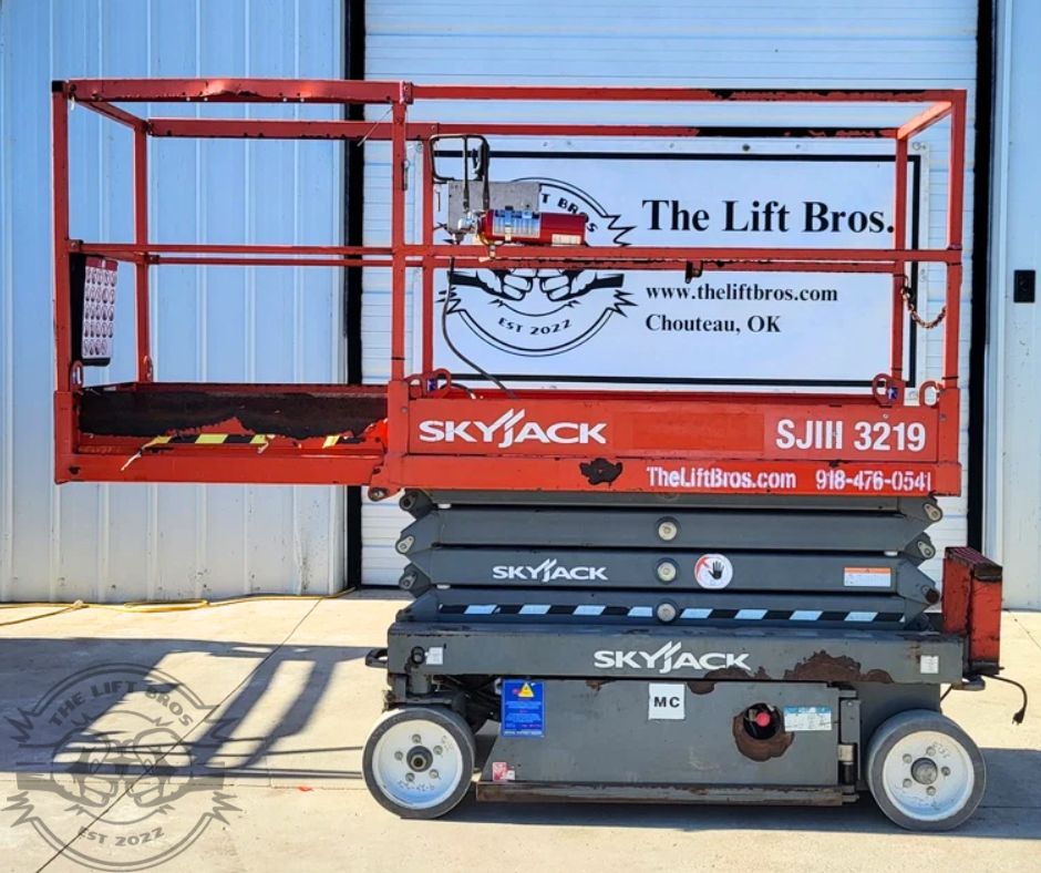 Red Skyjack SJIII 3219 scissor lift lowered, slide-out extension deck pushed out and the guardrails up