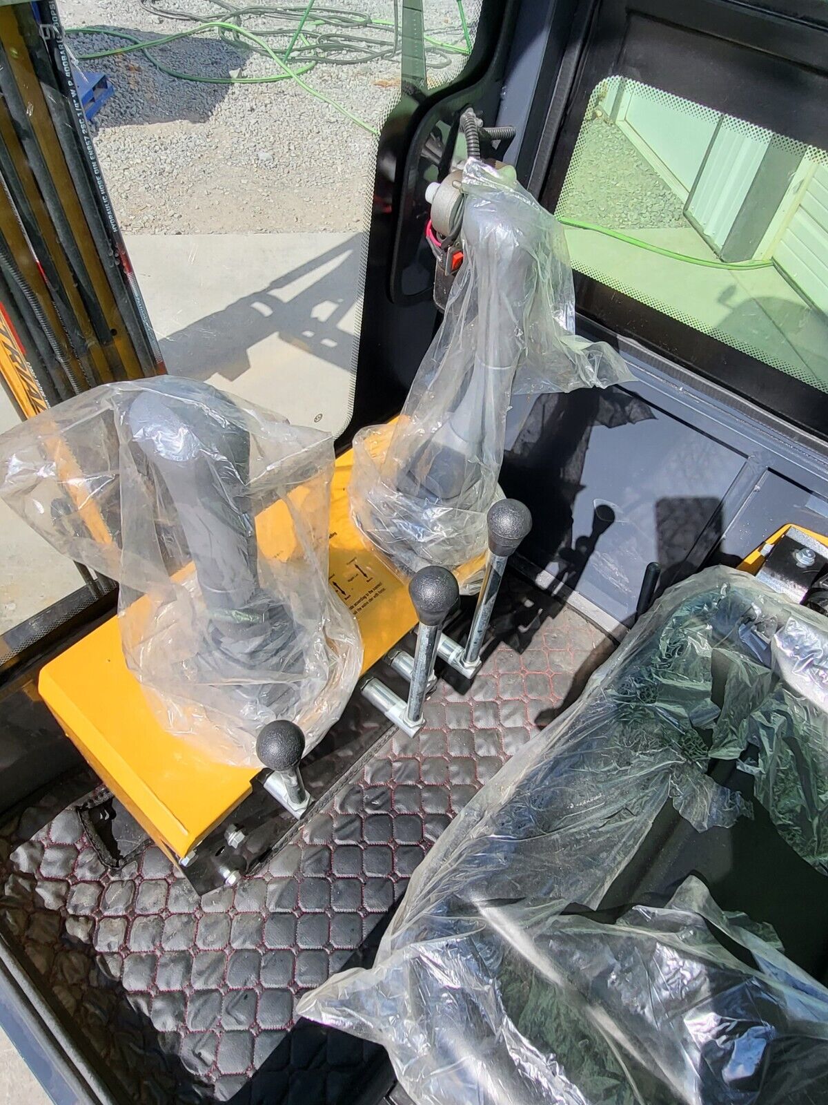 AGT H13R cab controls: two joysticks still in plastic wrap on the yellow console, travel and dozer levers