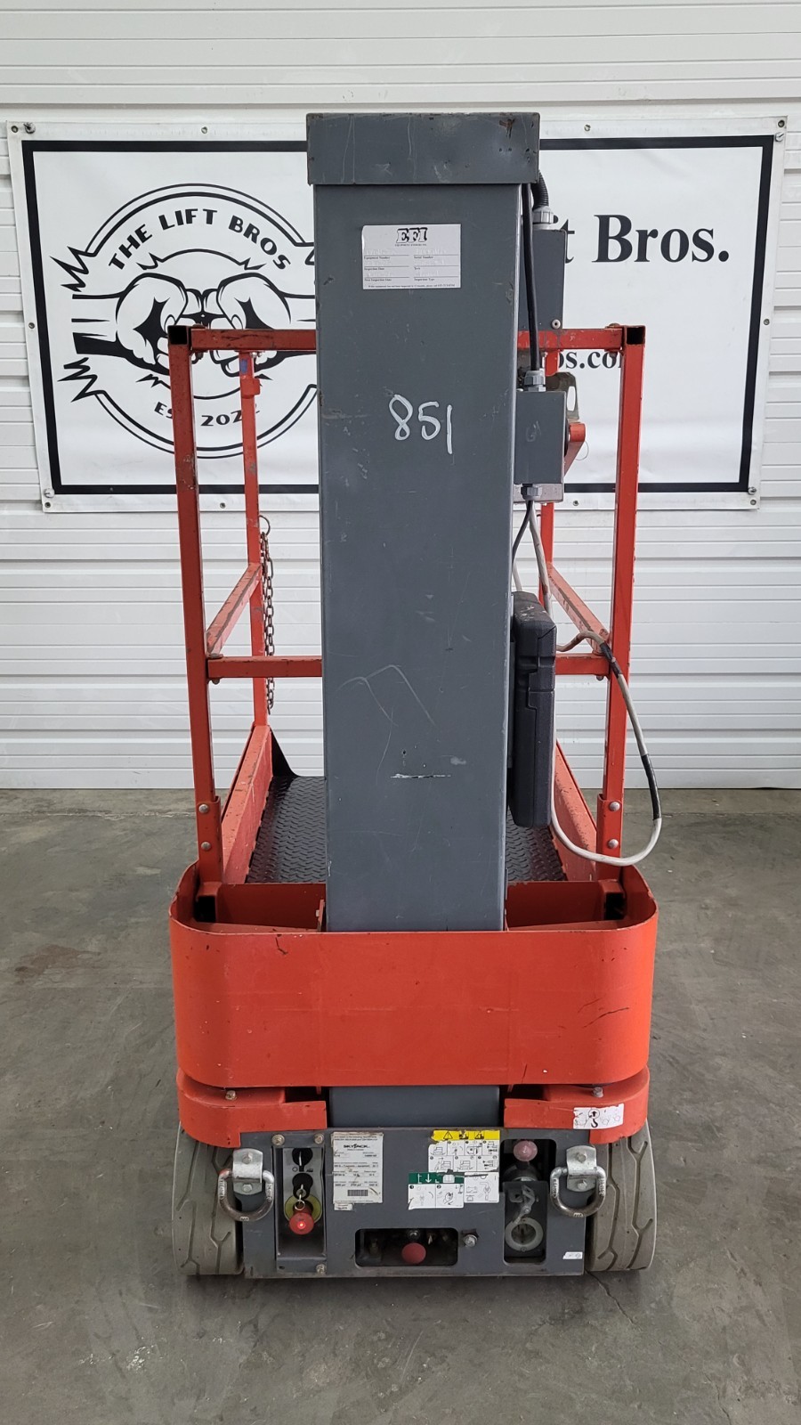 Orange Skyjack SJ16 vertical mast lift, rear view, gray mast column and platform