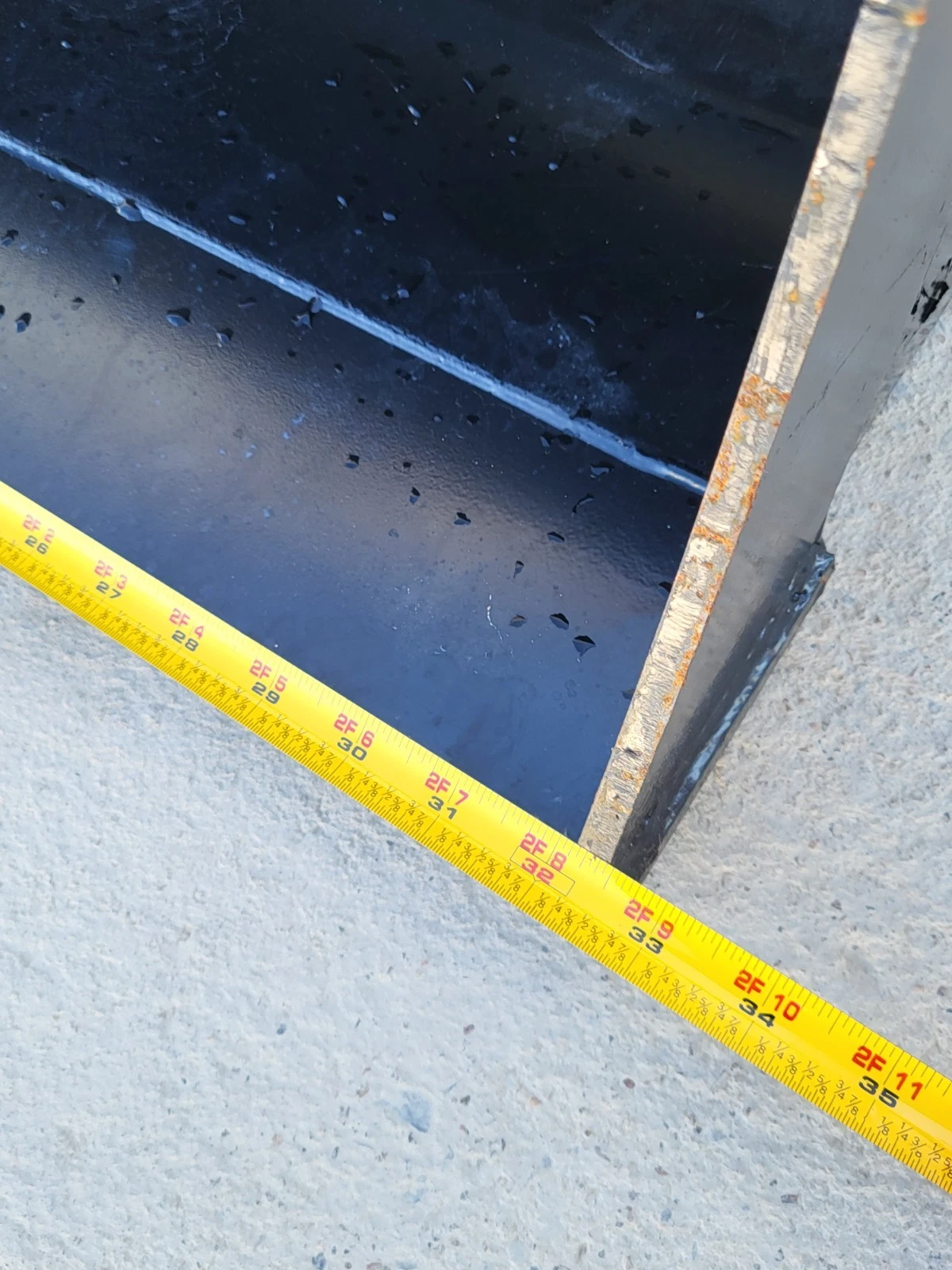 Tape measure along the bucket's cutting edge to the side plate, reading 32 inches