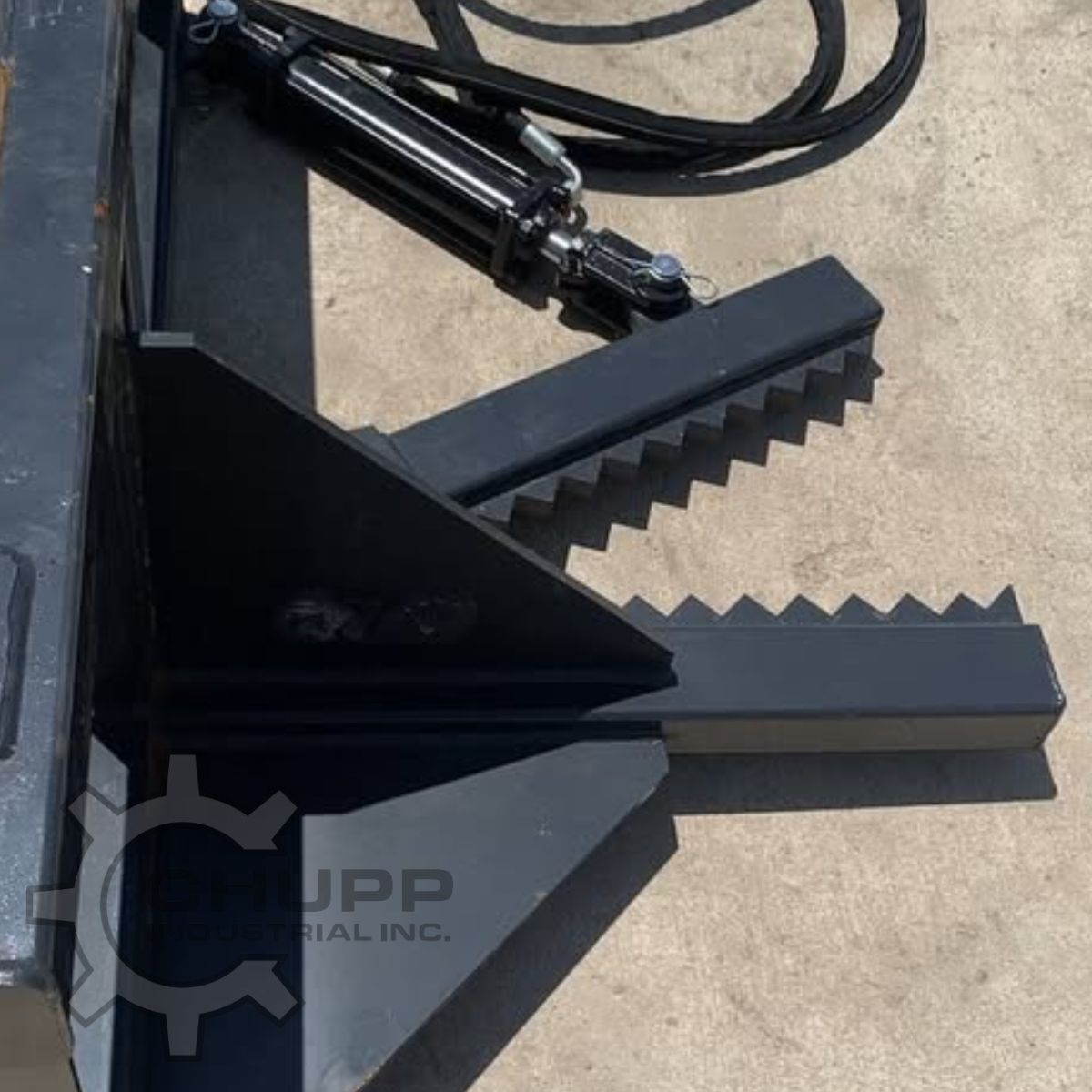 Tree and post puller jaws up close: serrated steel gripping teeth on both arms with the hydraulic cylinder behind