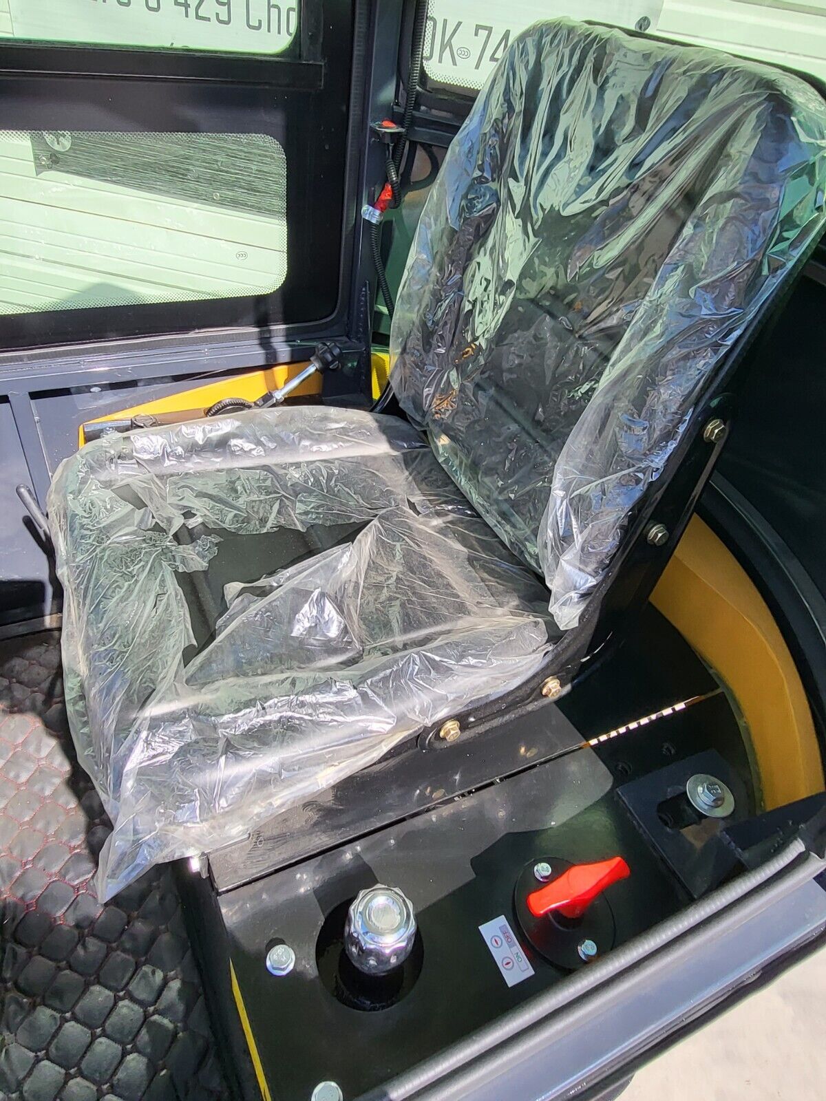 AGT H13R operator seat in factory plastic wrap, with the red battery disconnect switch on the deck behind it