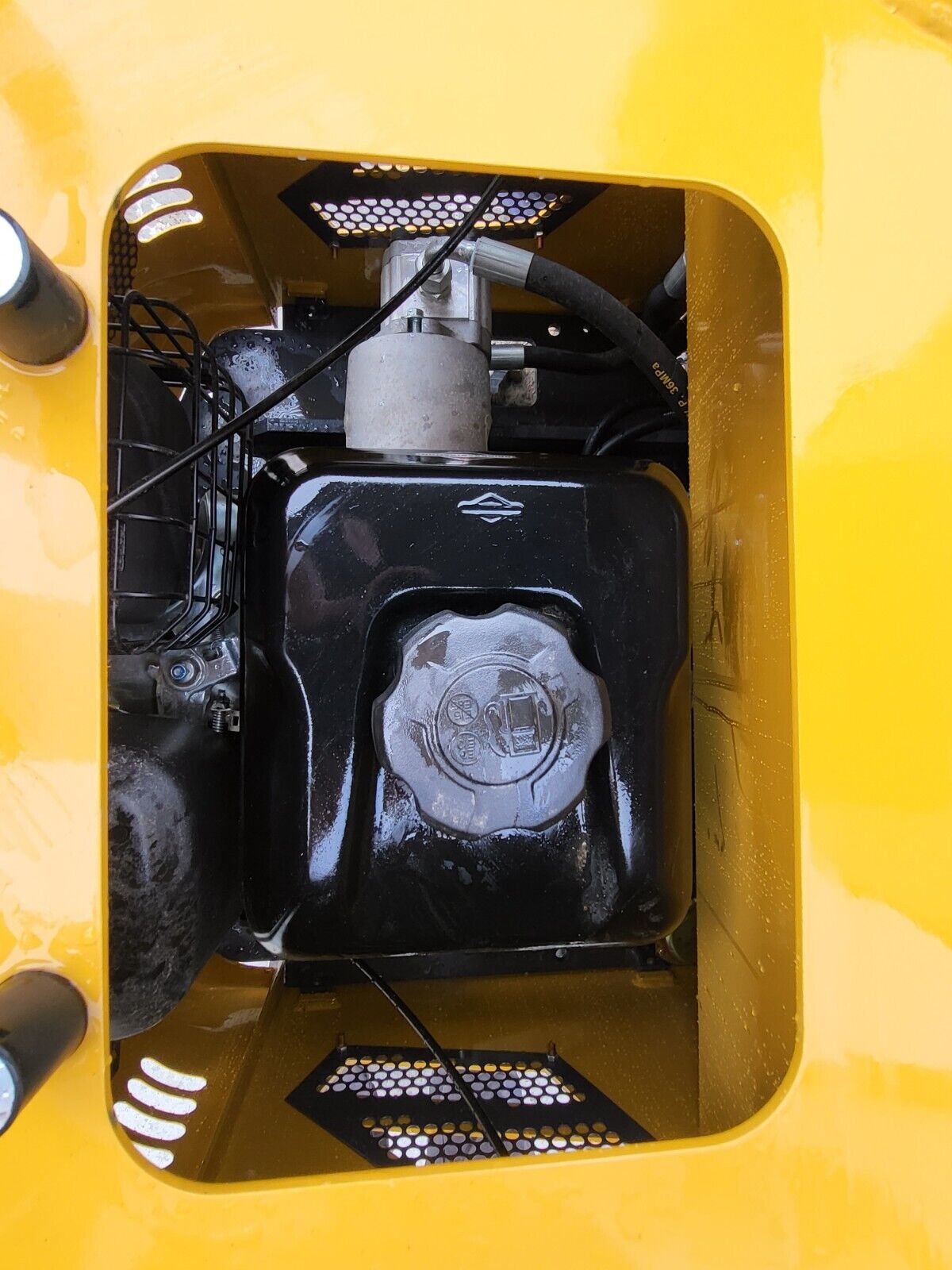 DM12-C fuel bay: black Briggs & Stratton tank and cap under the deck hatch, with the hydraulic filter and hose above