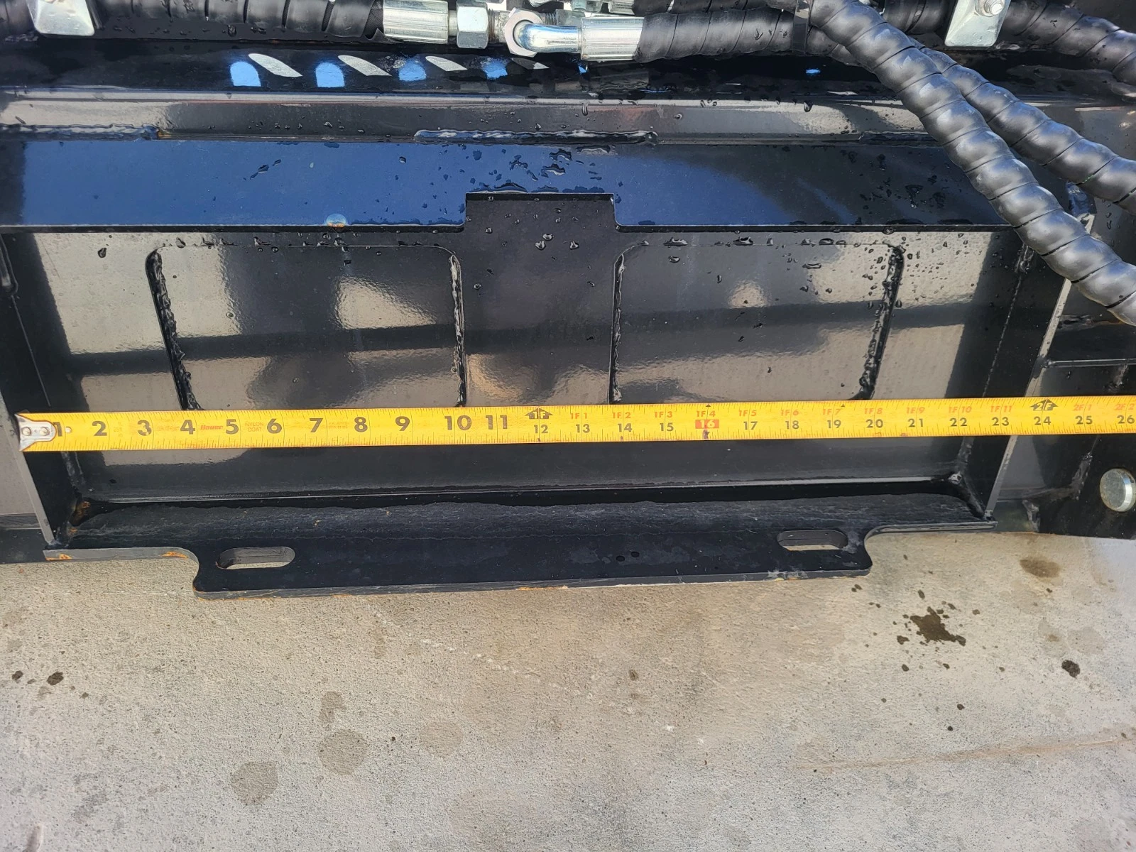Tape measure across the bucket's rear mount plate, reading about 26 inches