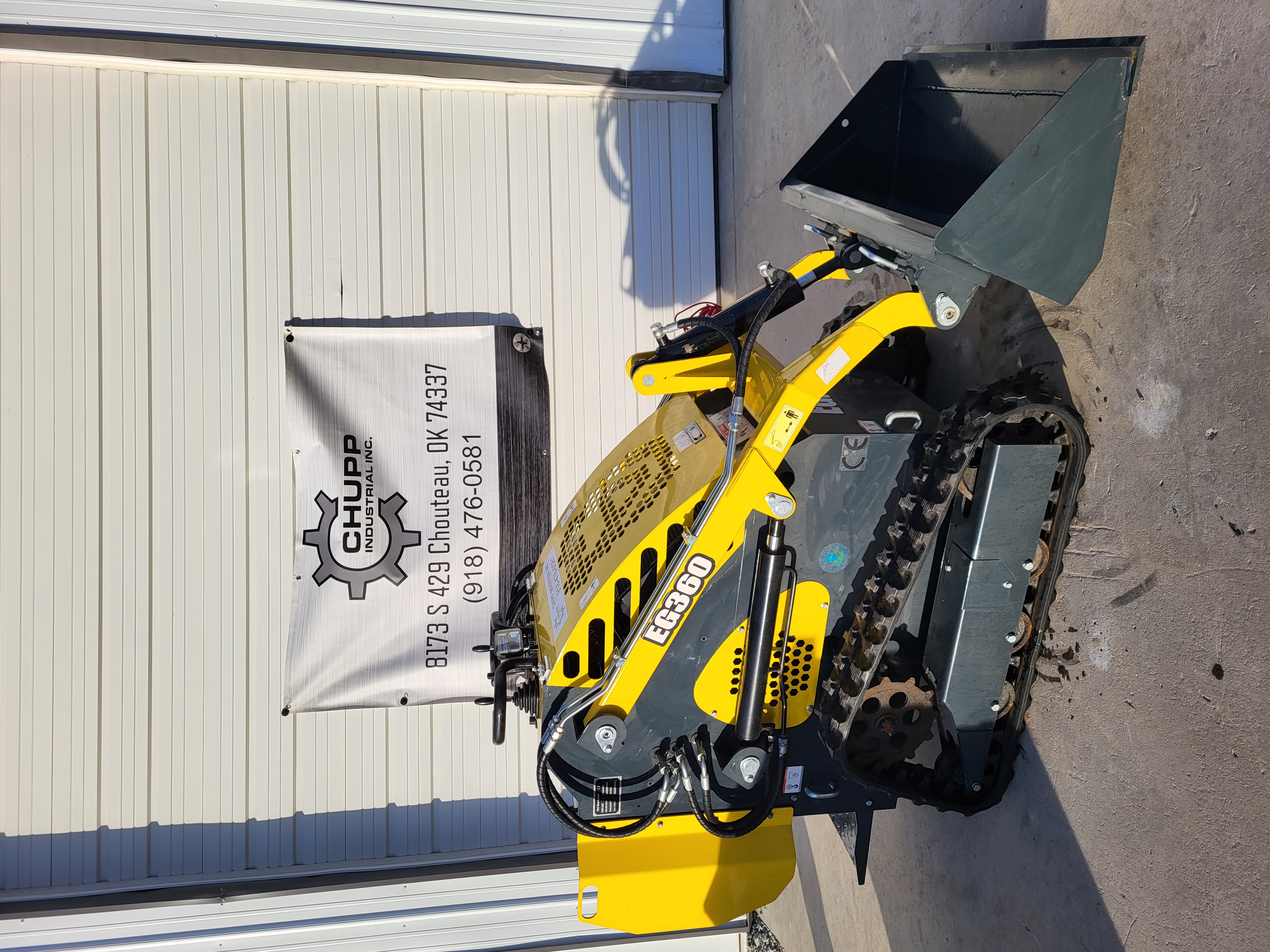 EGN EG360 mini skid steer: yellow stand-on loader with black bucket raised, hand levers and rubber tracks