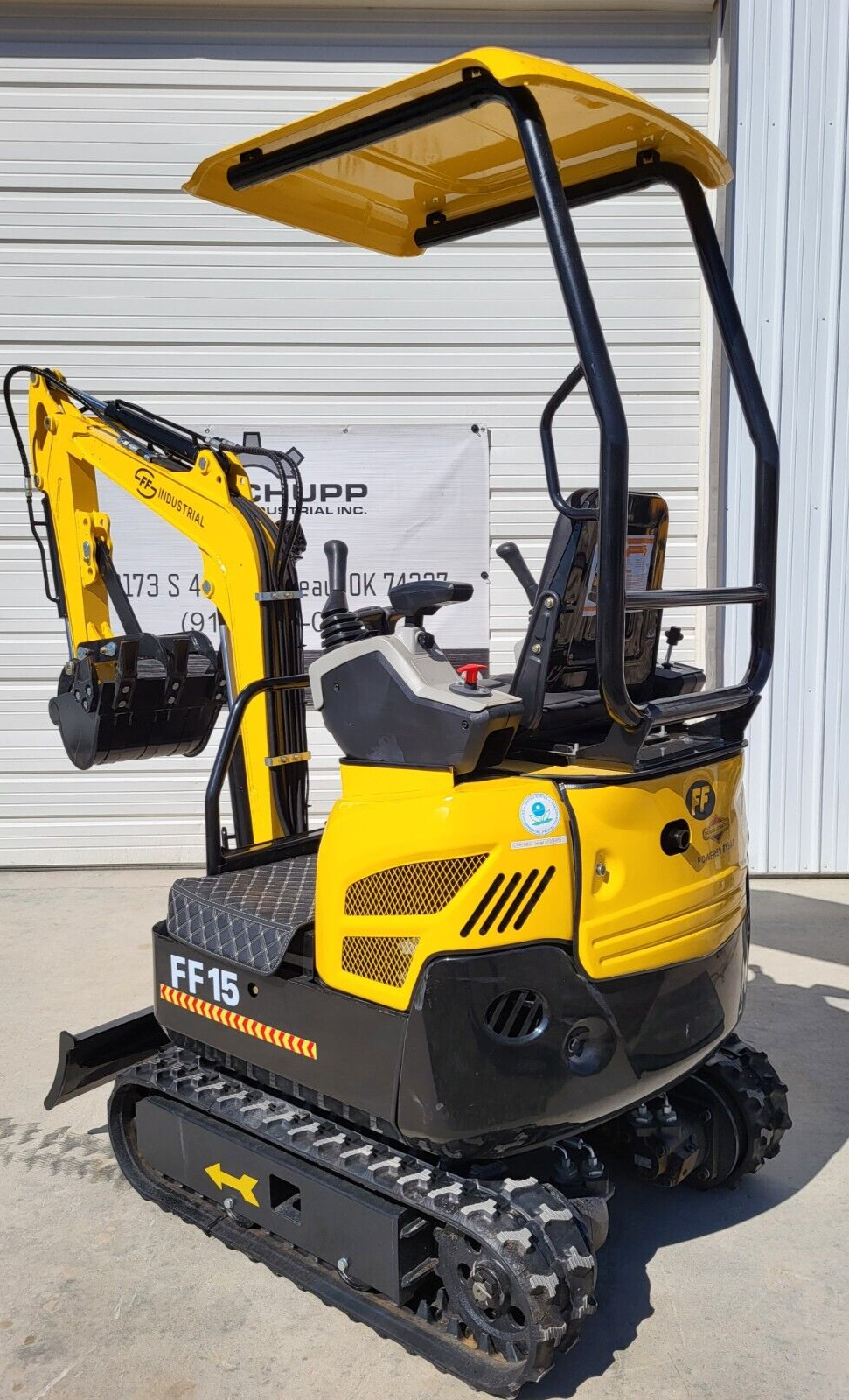 FF15 mini excavator, rear three-quarter: yellow canopy over the seat, vented engine cover, boom folded with the bucket