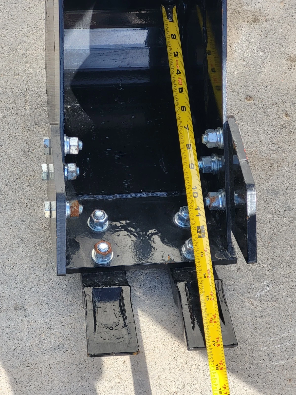 Tape measure down the depth of the trenching bucket, past the 16-inch mark, two teeth at the lip