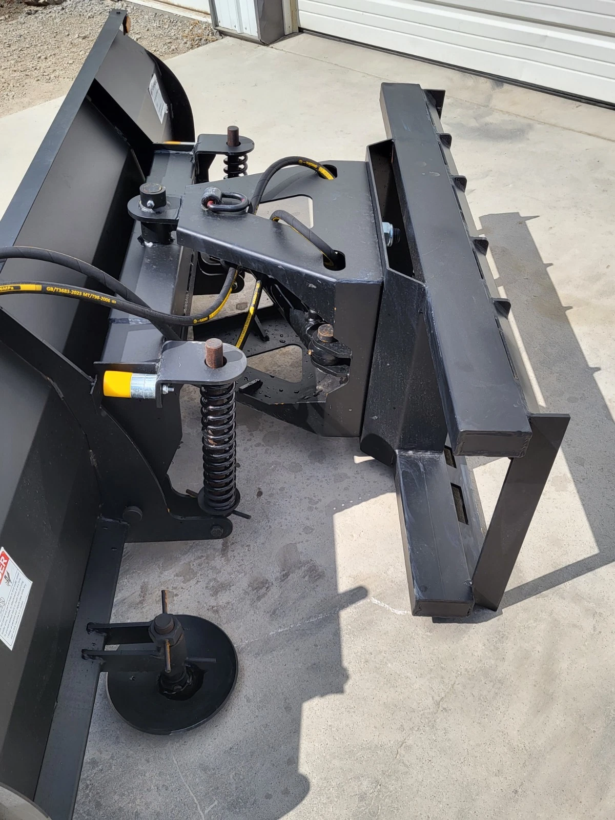 Push blade angle adjustment: dual hydraulic cylinders with coil springs and a manual hand crank