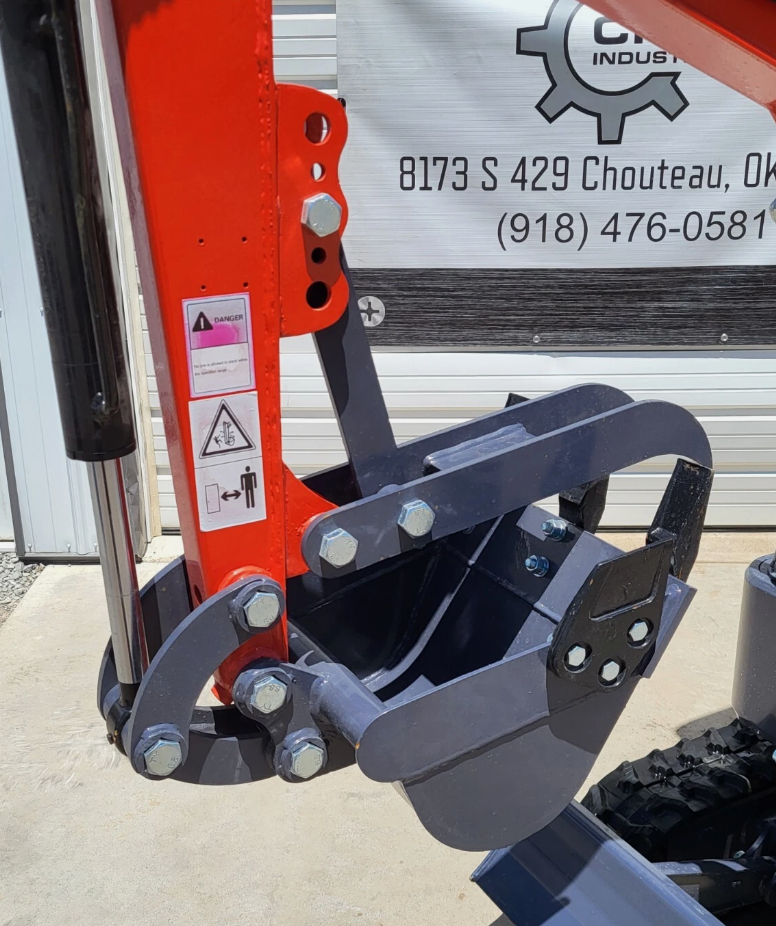 MX15RX digging bucket and fixed thumb linkage on the orange boom arm, with pinch-point warning decals