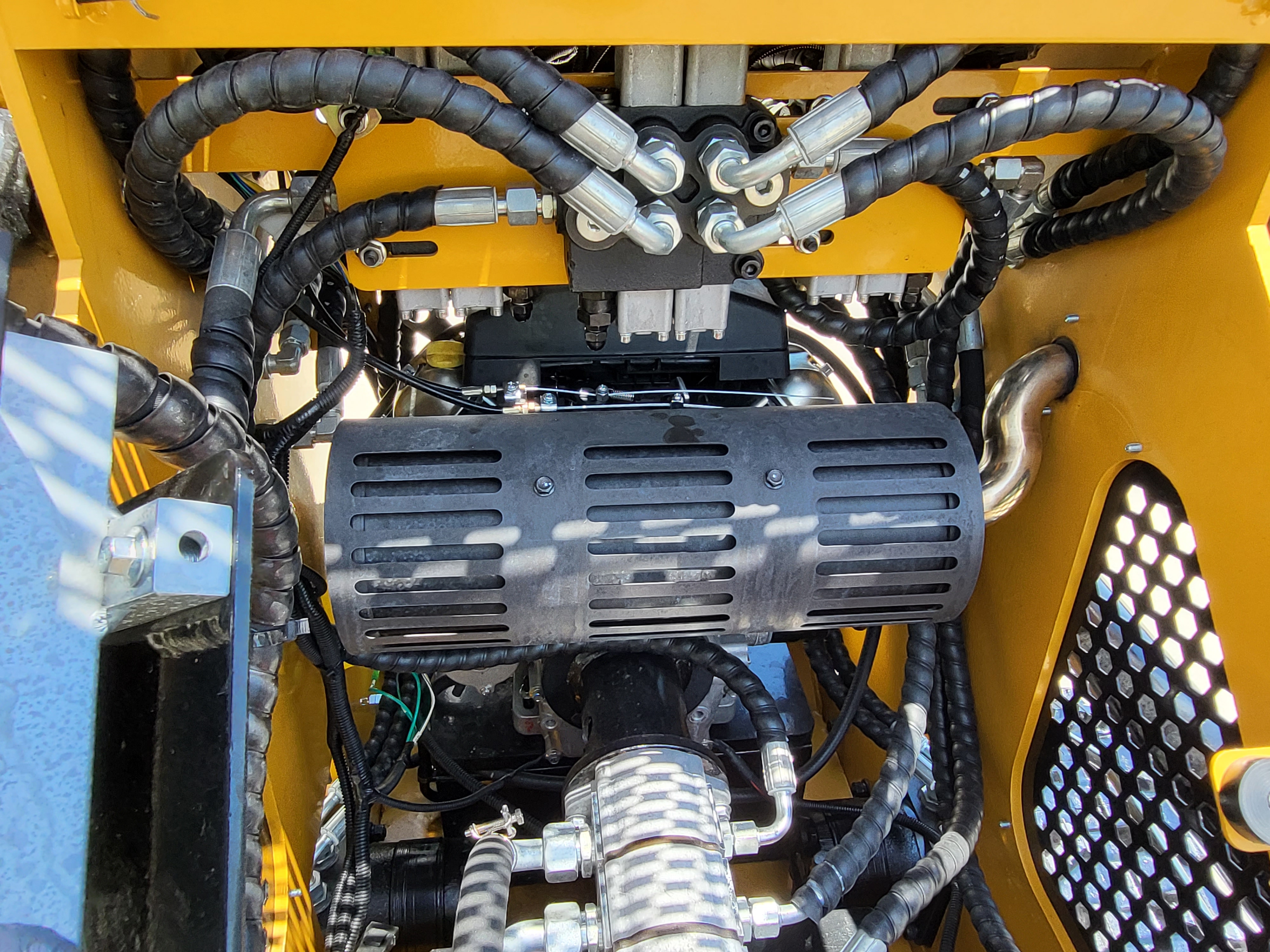 AGT CRT23 hydraulics: stacked control valve bank feeding braided hoses over the shielded muffler and exhaust