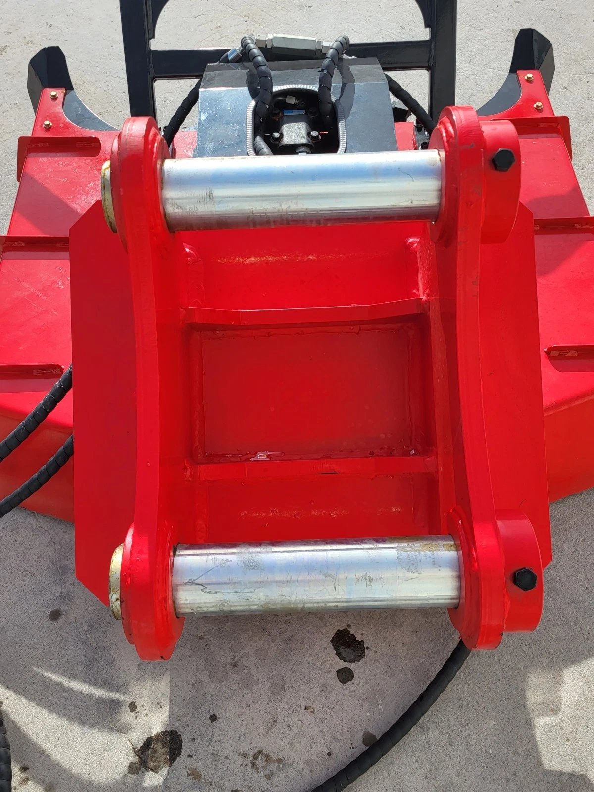 Top of the red Captok disc mulcher: twin polished mounting pins, hydraulic motor and spiral-wrapped hoses
