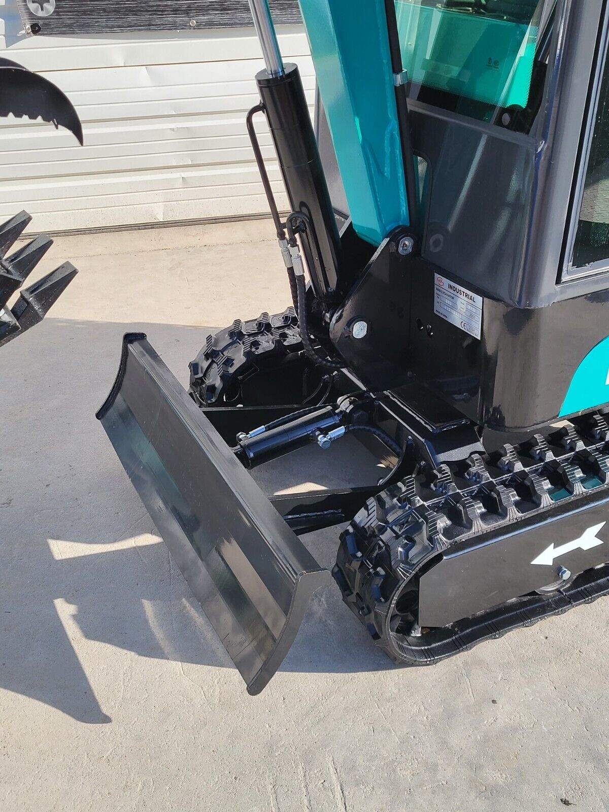 FF13 mini excavator front end: raised black dozer blade with its cylinder, rubber tracks and the FF Industrial data plate