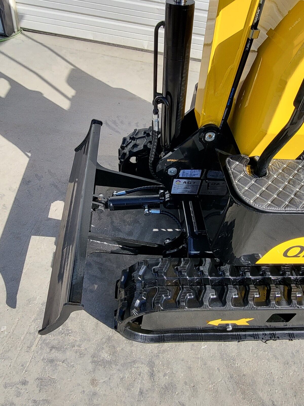 AGT QH12R backfill blade and its hydraulic cylinder beside the rubber track, with the AGT serial plate