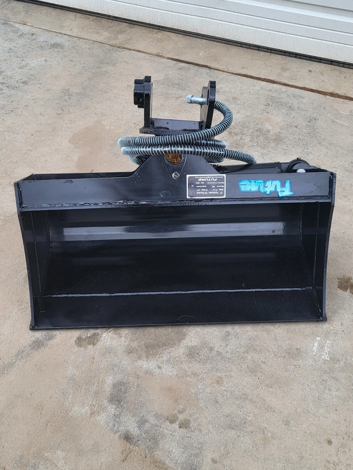 Black Future 3T hydraulic tilt bucket head-on, wide smooth cutting edge and tilt head with hoses