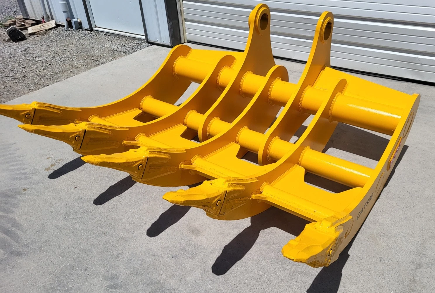 Yellow TOFT10R excavator rake, five curved tines with bolted tips and twin pin-boss mounting arms