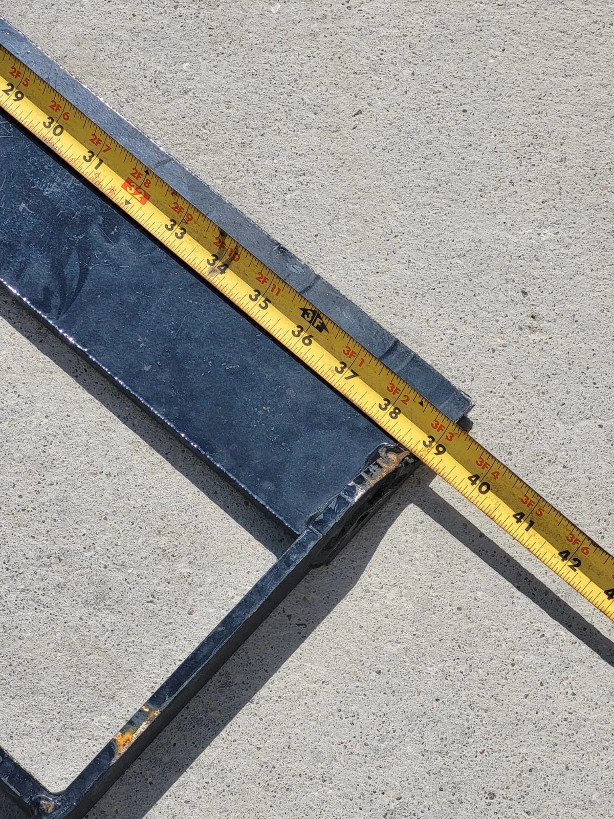 Tape measure along the land leveler's steel side rail, reading about 39 inches at the end weld