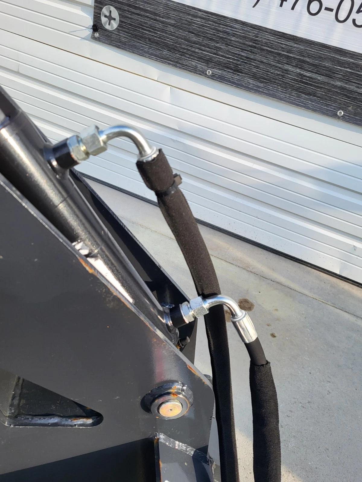 Hydraulic hose with a 90-degree fitting and protective wrap on the log grapple frame