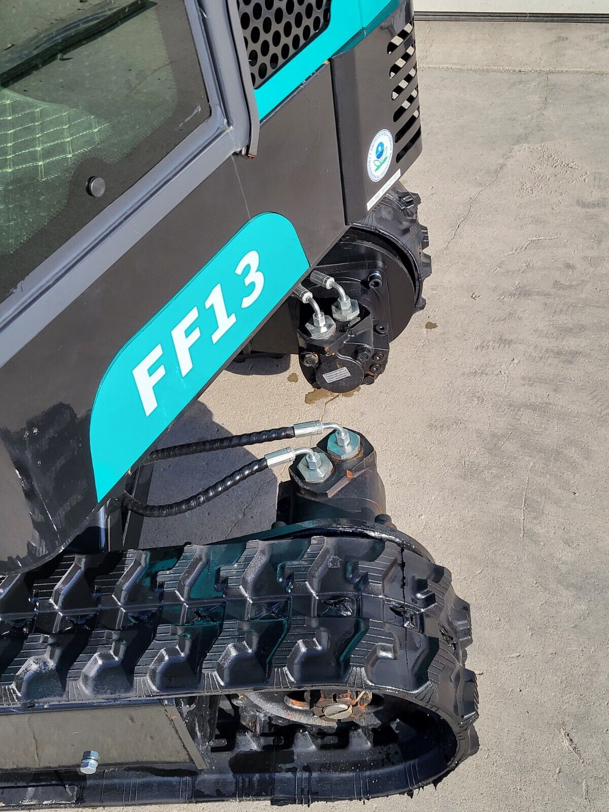 FF13 final drive motor and hydraulic hoses at the rubber track, below the model decal on the black upper body