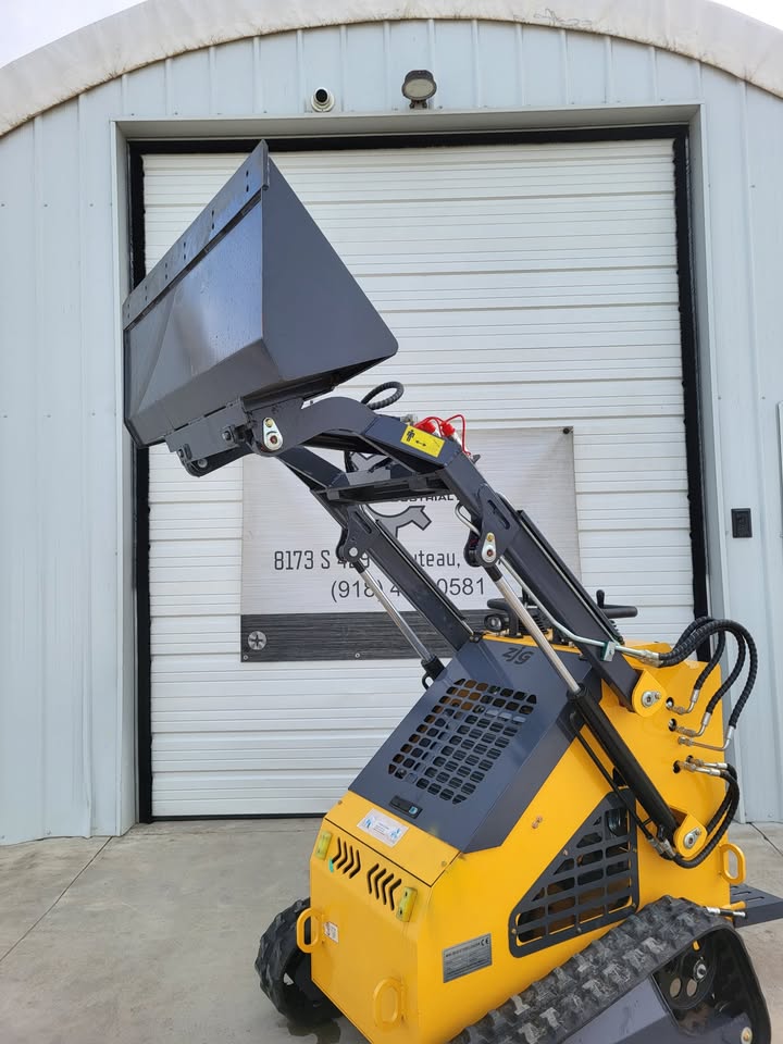 ZJG-380 mini skid steer with the dirt bucket raised on its lift arms, yellow body on rubber tracks