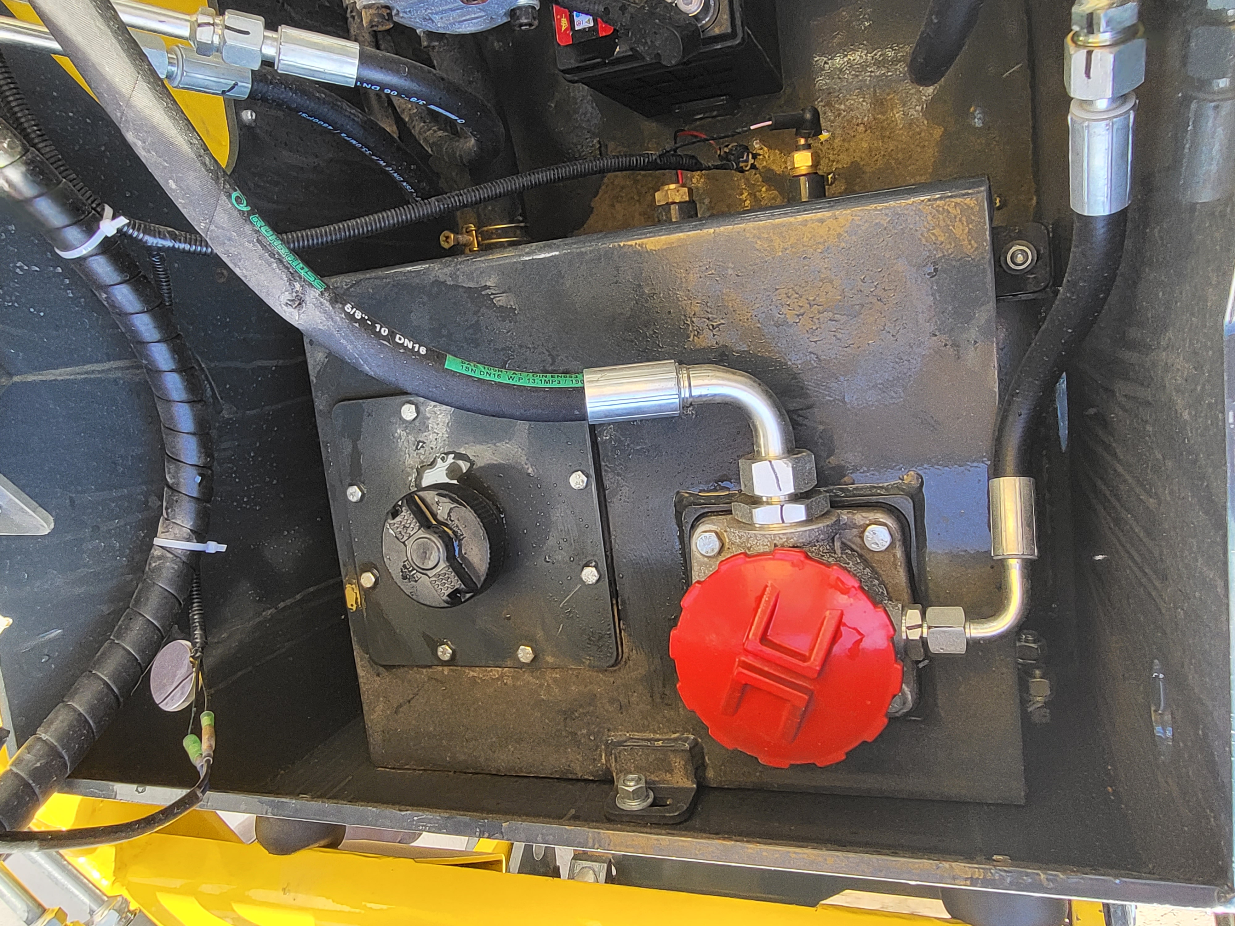 EG360 steel hydraulic tank with red hydraulic fill cap and black fuel cap, return hoses running to the pump