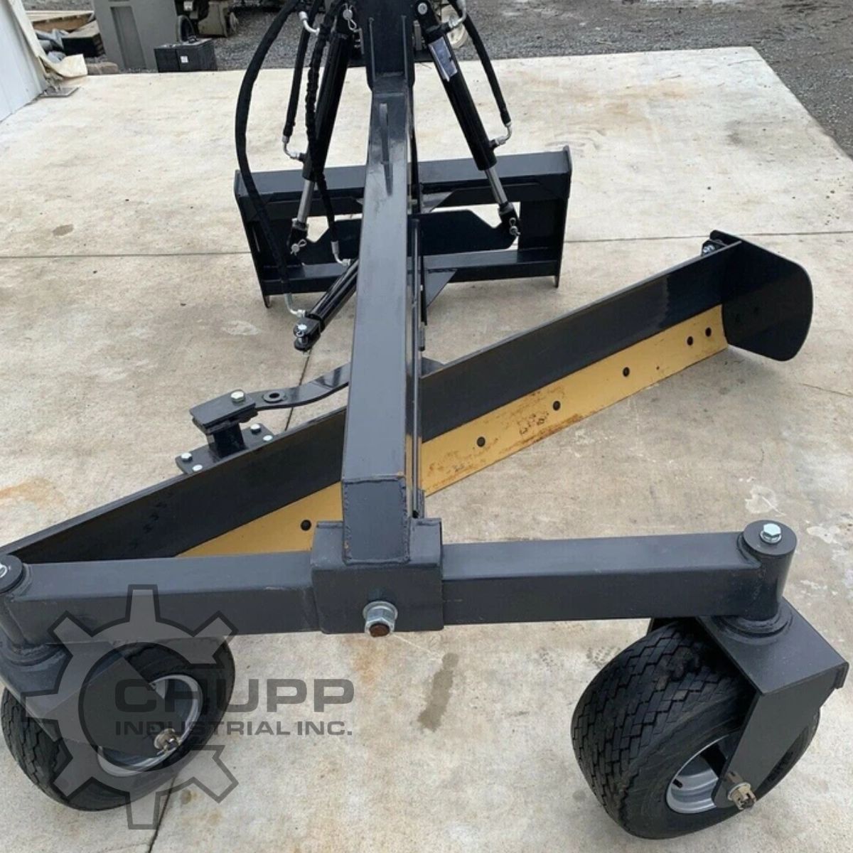 Landhonor grading blade from behind: black moldboard with yellow cutting edge, gauge wheels and quick-attach frame