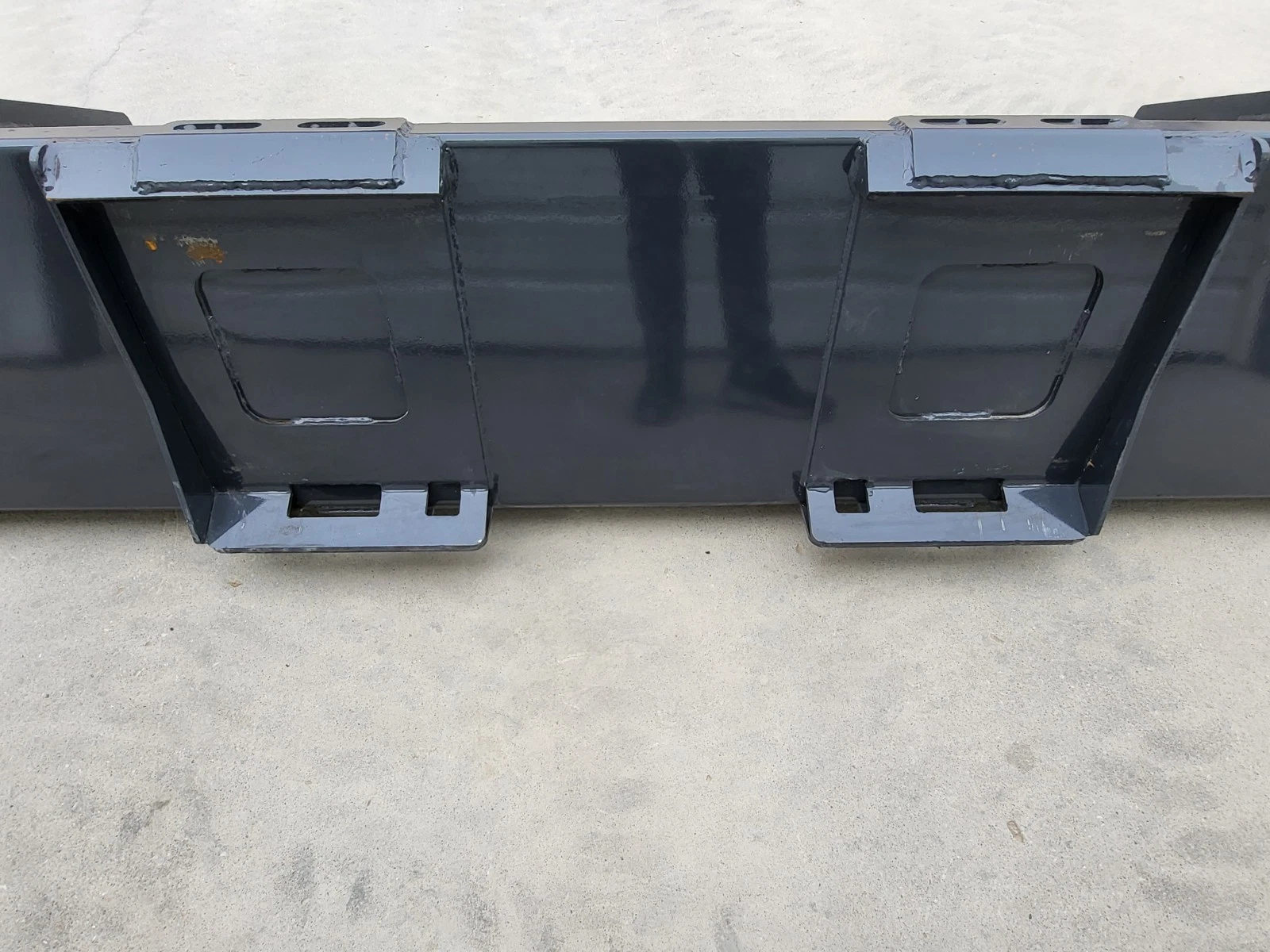 Bucket's rear quick-attach brackets, latch slots and welded gussets across the back panel