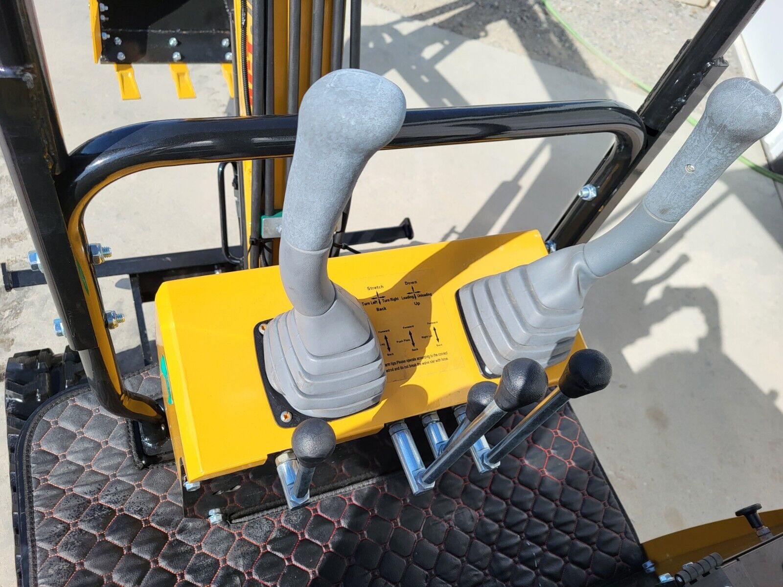 AGT H12R mini excavator operator controls: two joysticks, steel track levers and the padded seat