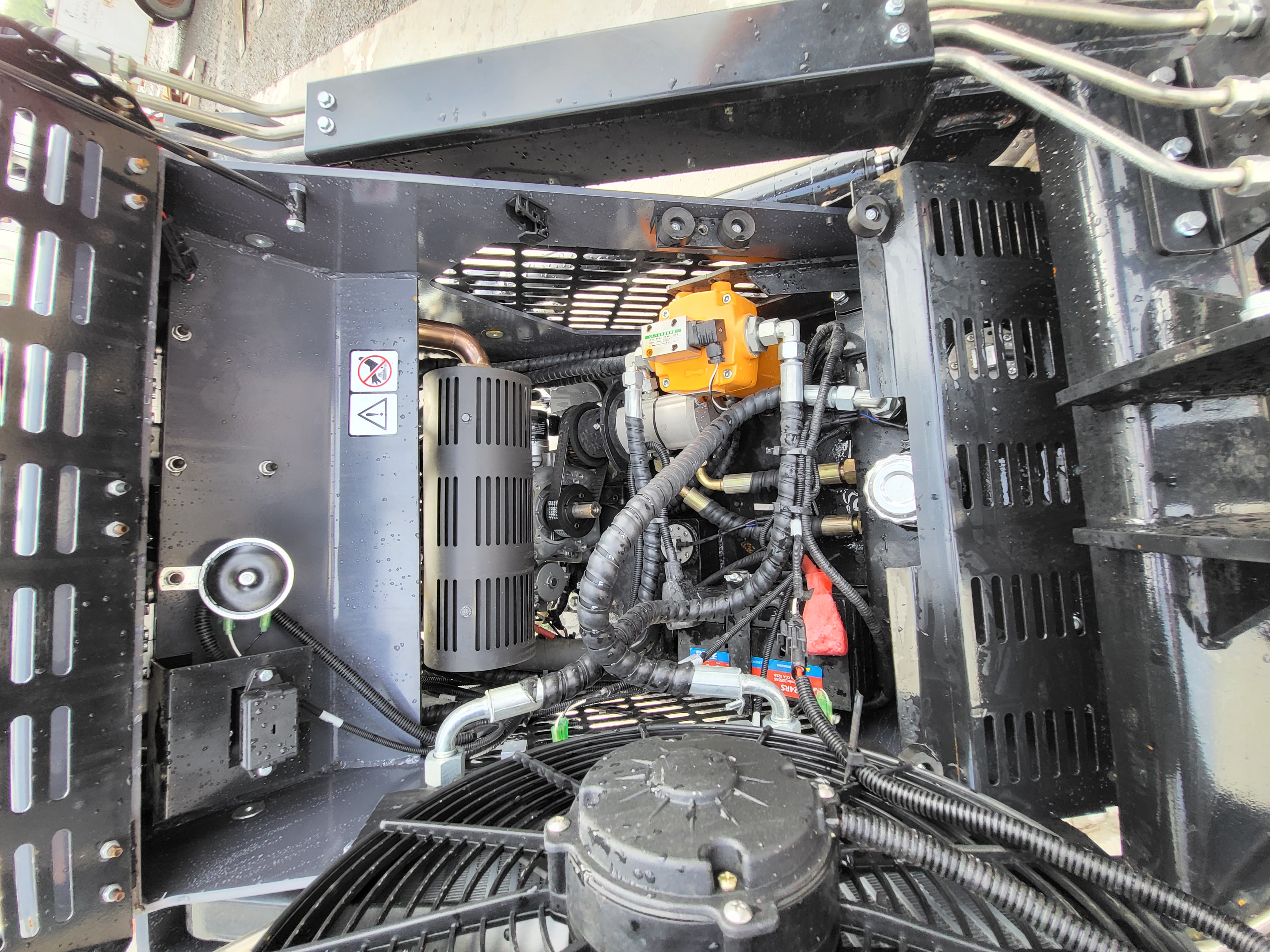 KRT23 engine bay: orange hydraulic control valve, black air cleaner, wiring harness and the electric cooling fan